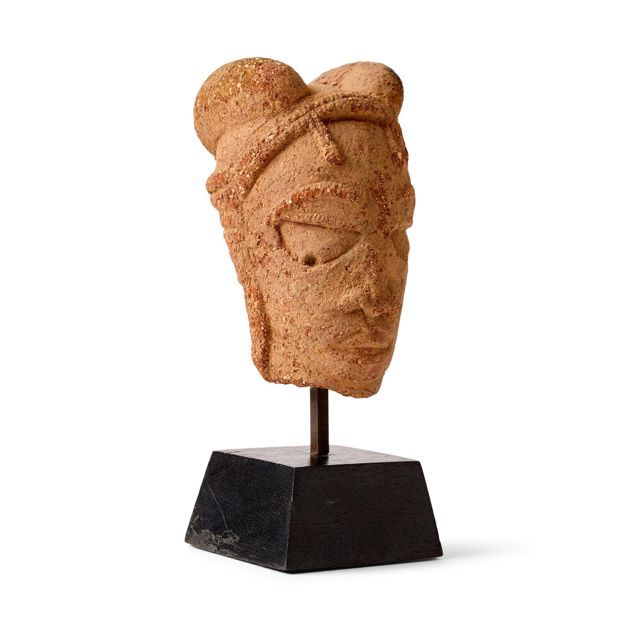 Resti di testa in terracotta su base di legno affusolata