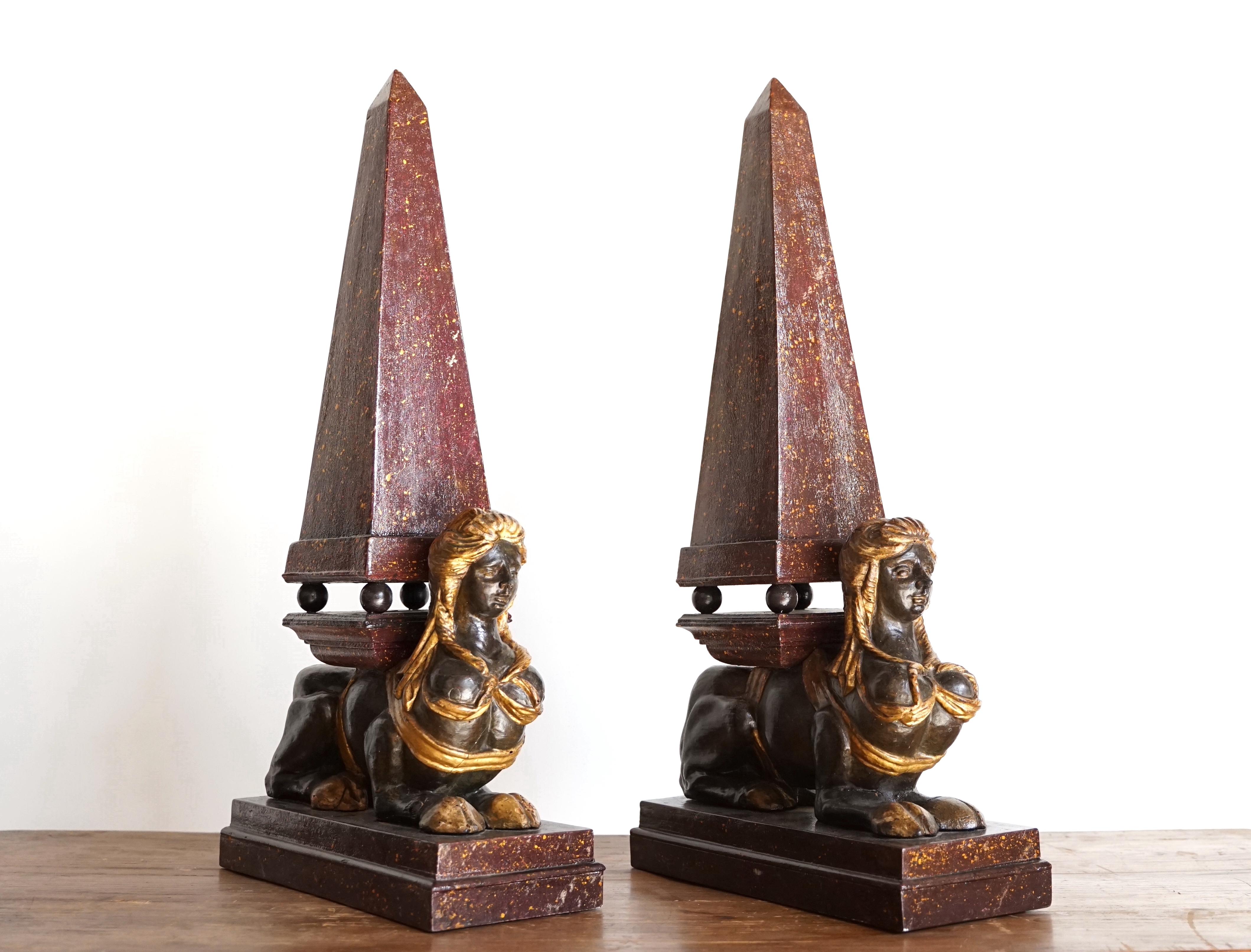 Splendid pair of important lacquered wooden obelisks: the sphinxes are embellished with elegant gilded festoons while the obelisks are exceptionally lacquered in imitation porphyry. The ensemble makes the pair very elegant and sumptuous, giving them