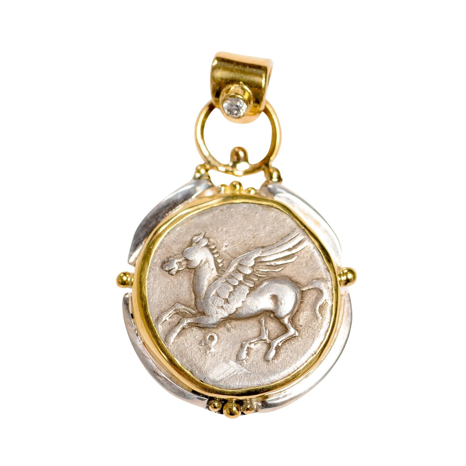 An authentic CORINTH Silver Stater Coin (circa 386-307 BC), set in a custom 22k gold and sterling silver bezel with a 22k gold bail (which has a diamond accent). The obverse, or front, side of this coin features Pegasus in flight, Koppa below. On