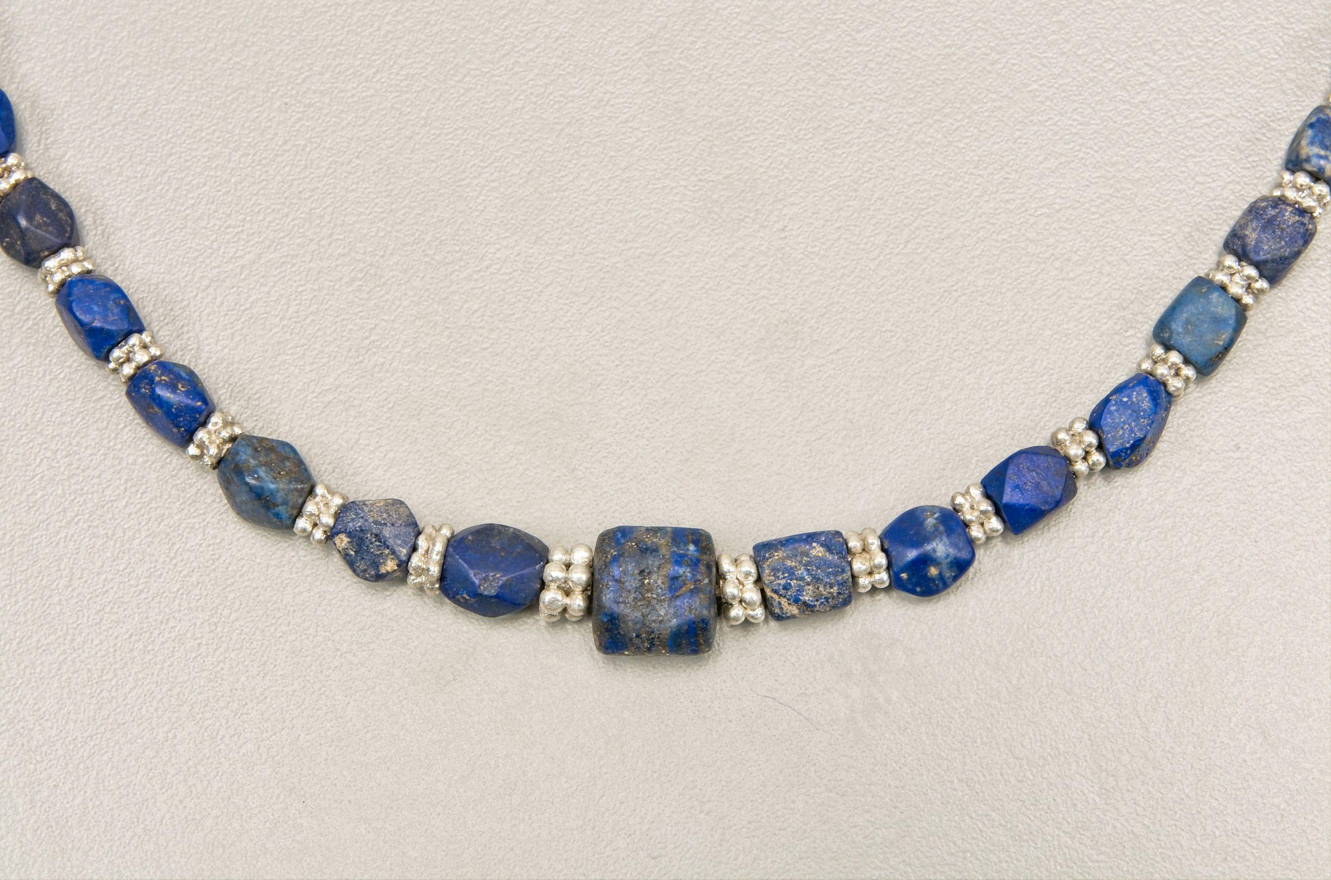 Siebenundvierzig antike eckenlose Lapislazuli-Würfelperlen wechseln sich mit zwei Schichten granulierter Silberringperlen ab. Die Größe der Perlen ist von der Vorderseite zur Rückseite der Kette hin abgestuft. Die mittlere Perle ist 1,2 cm lang,