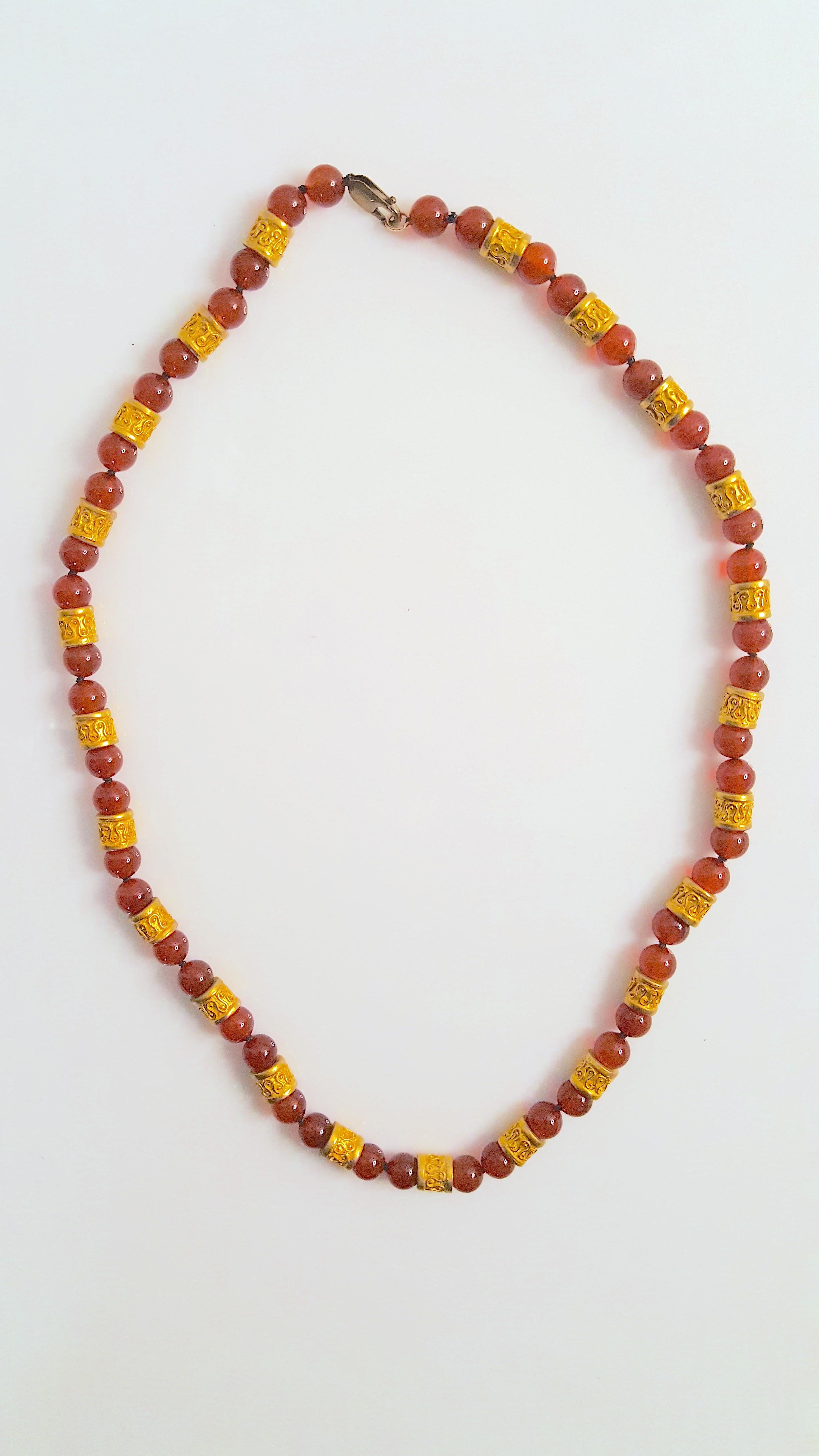 Featuring yellow-gold sinuous-pattern rondelles and carnelian rock-crystal round 8mm beads, this ancient-revival heavy necklace is knotted in stations along a black silk cord. The gold 8mm rondelles are textured in high-relief with alternating loops