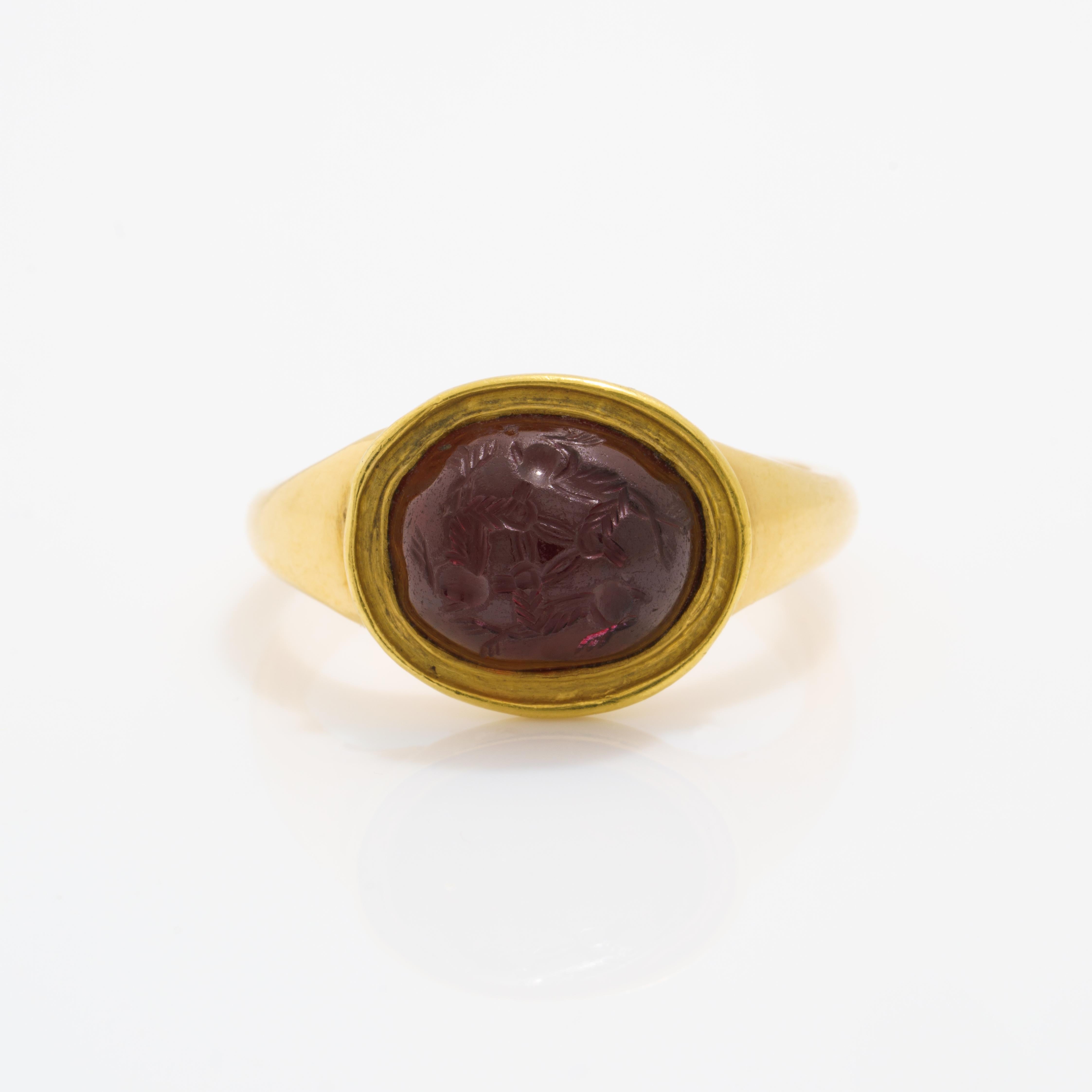 An ancient garnet intaglio depicting three chasing hares, mounted in a heavy 18 karat gold ring. The
carved garnet intaglio is Roman and dates back to the 1st-2nd century. 
Intaglio measures 1 cm at widest
Set in heavy 18 Karat Gold newer