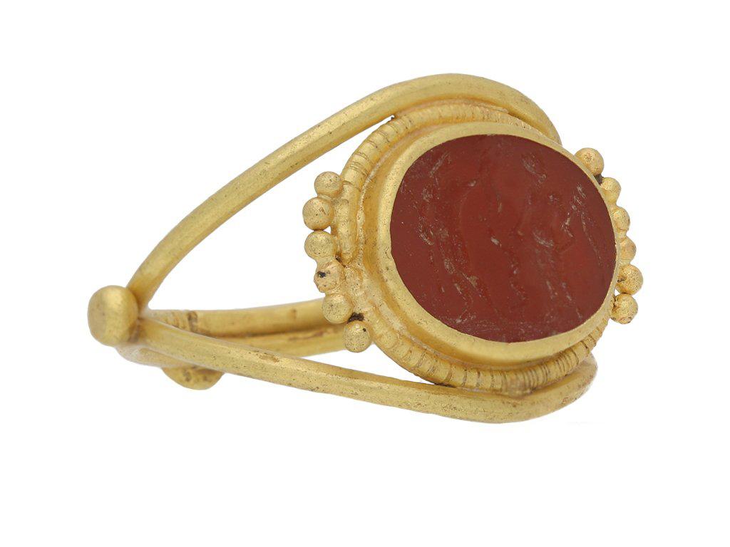 Ancient Roman Apollo and Salus intaglio ring. Set with an oval cornelian intaglio intricately carved with the god Apollo with staff and laurel wreath, the goddess Salus with a snake entwined rod, and staff of Asclepius in between, in a closed back