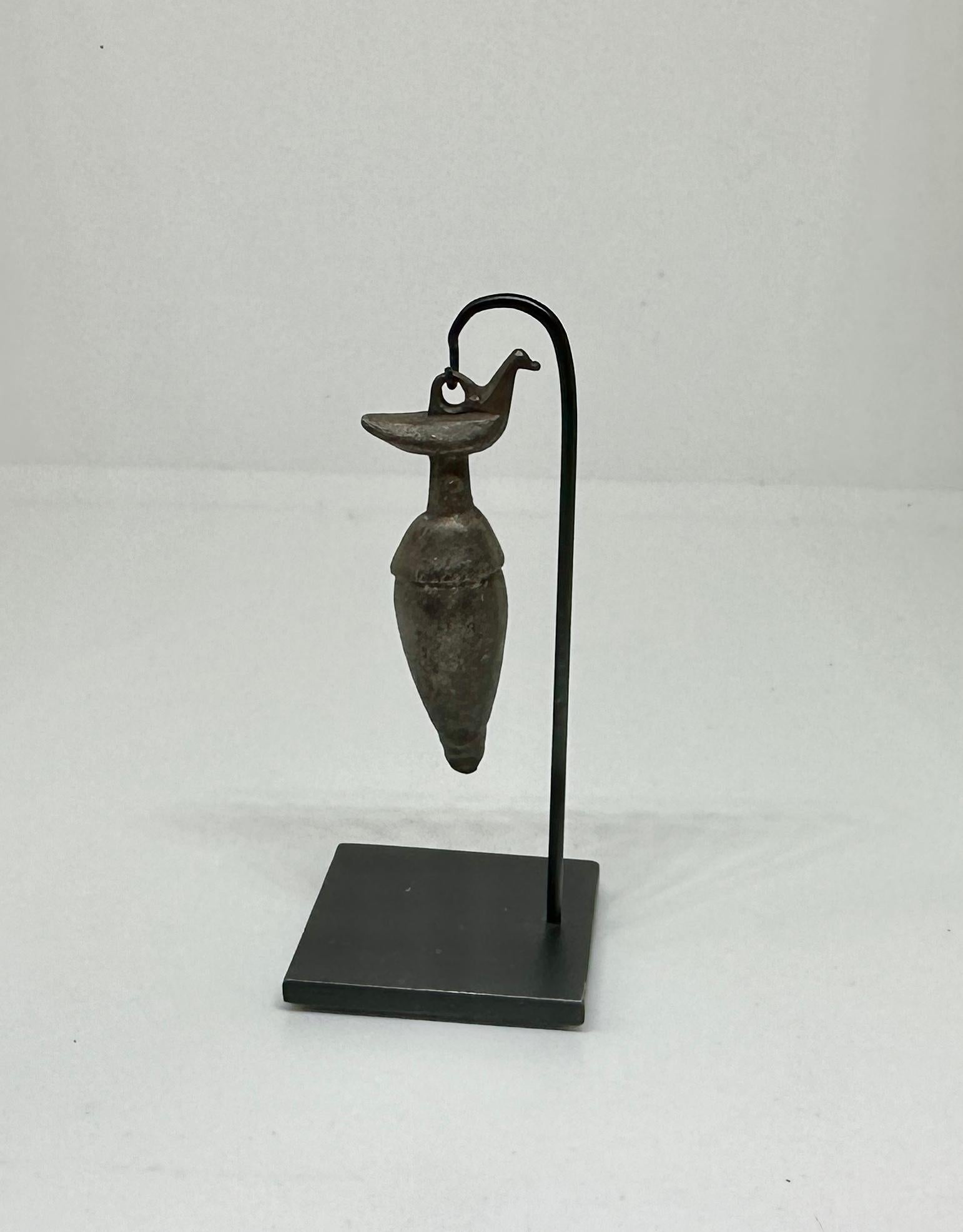 Scopri l'eleganza dell'antichità con questo ciondolo a forma di uccello romano su un'urna.  L'immagine di questo antico ciondolo romano in bronzo è estremamente rara e meravigliosa.  L'amuleto risale al I-II secolo d.C. (1-200 d.C.).   Questo antico