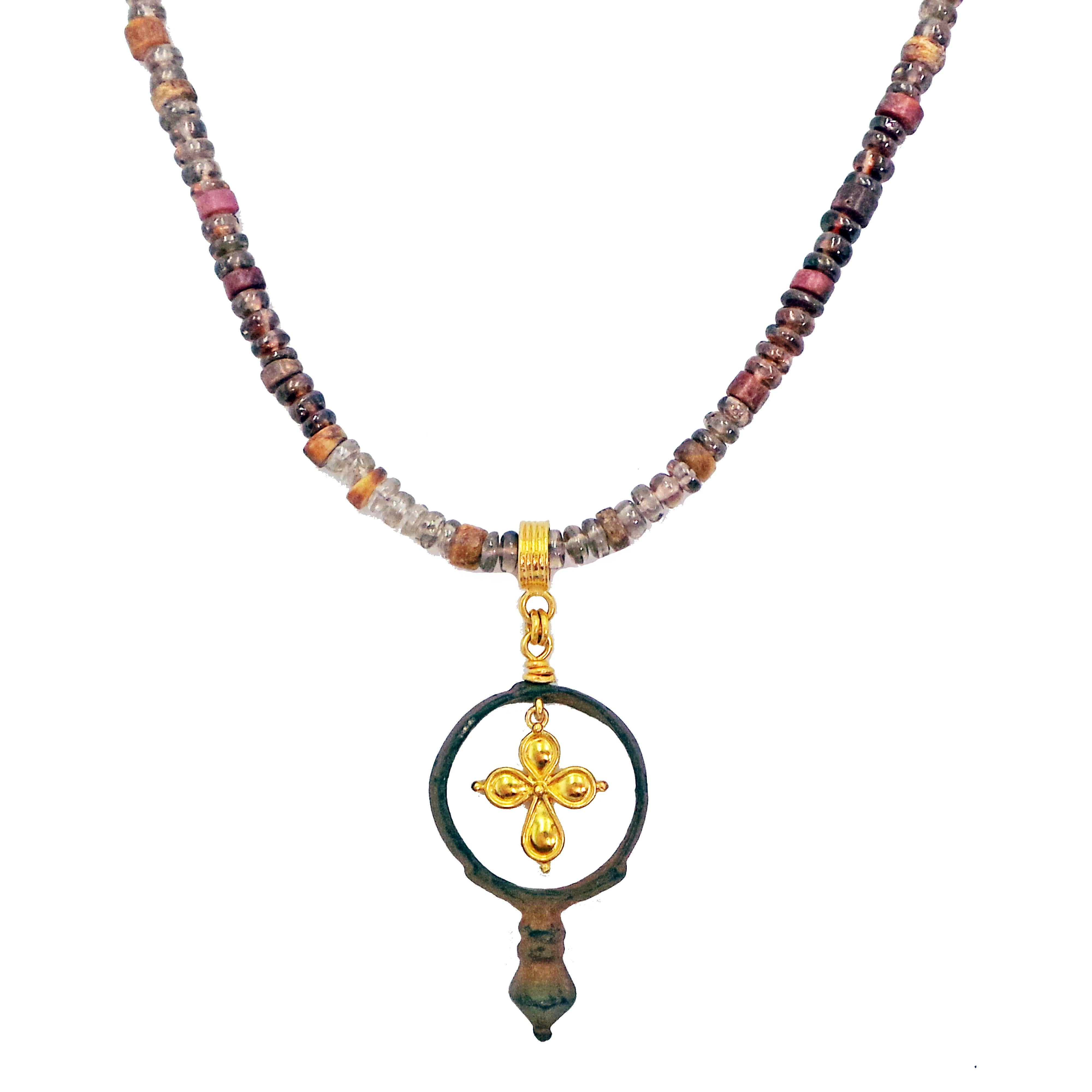 Authentique anneau romain antique en bronze et pendentif en forme de croix en or jaune 22k sur un collier en perles de spinelles et de coquilles d'huîtres épineuses de couleur rouge, violette et brune. Le collier est terminé par une fermeture à