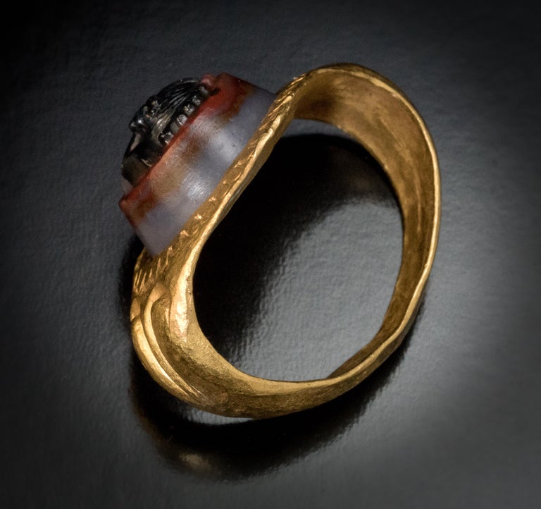 Roman Empire, 2nd – 3rd century A.D.

This massive solid gold ring with broad shoulders is of a very fine workmanship. The ring is crafted in high karat gold (about 24K). It is centered with a conical banded three layer agate  superbly carved with a