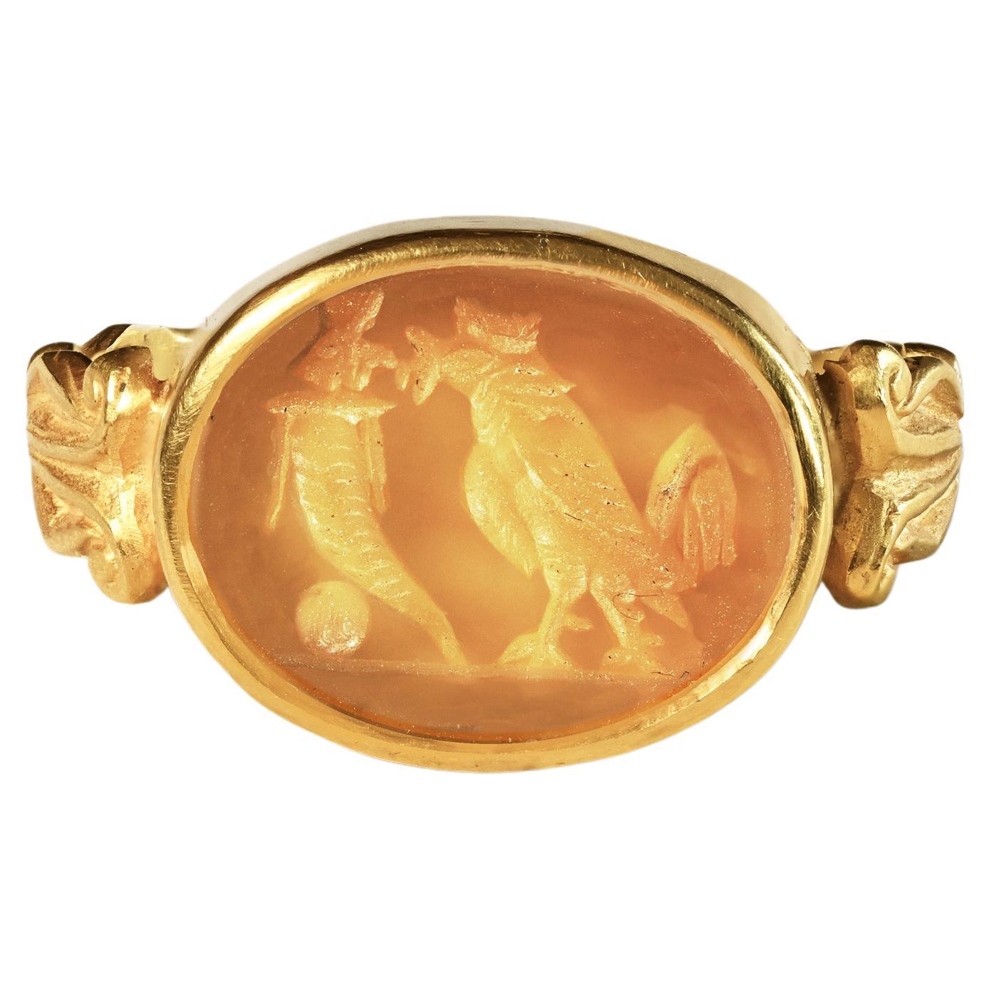 Dieser Ring aus 18-karätigem Gold zeigt ein authentisches römisches Karneol-Intaglio aus dem 1. bis 2. Jahrhundert nach Christus. Der Stichtiefdruck stellt Hahn und Füllhorn dar.
In der griechischen und römischen Antike war der Hahn ein wichtiges