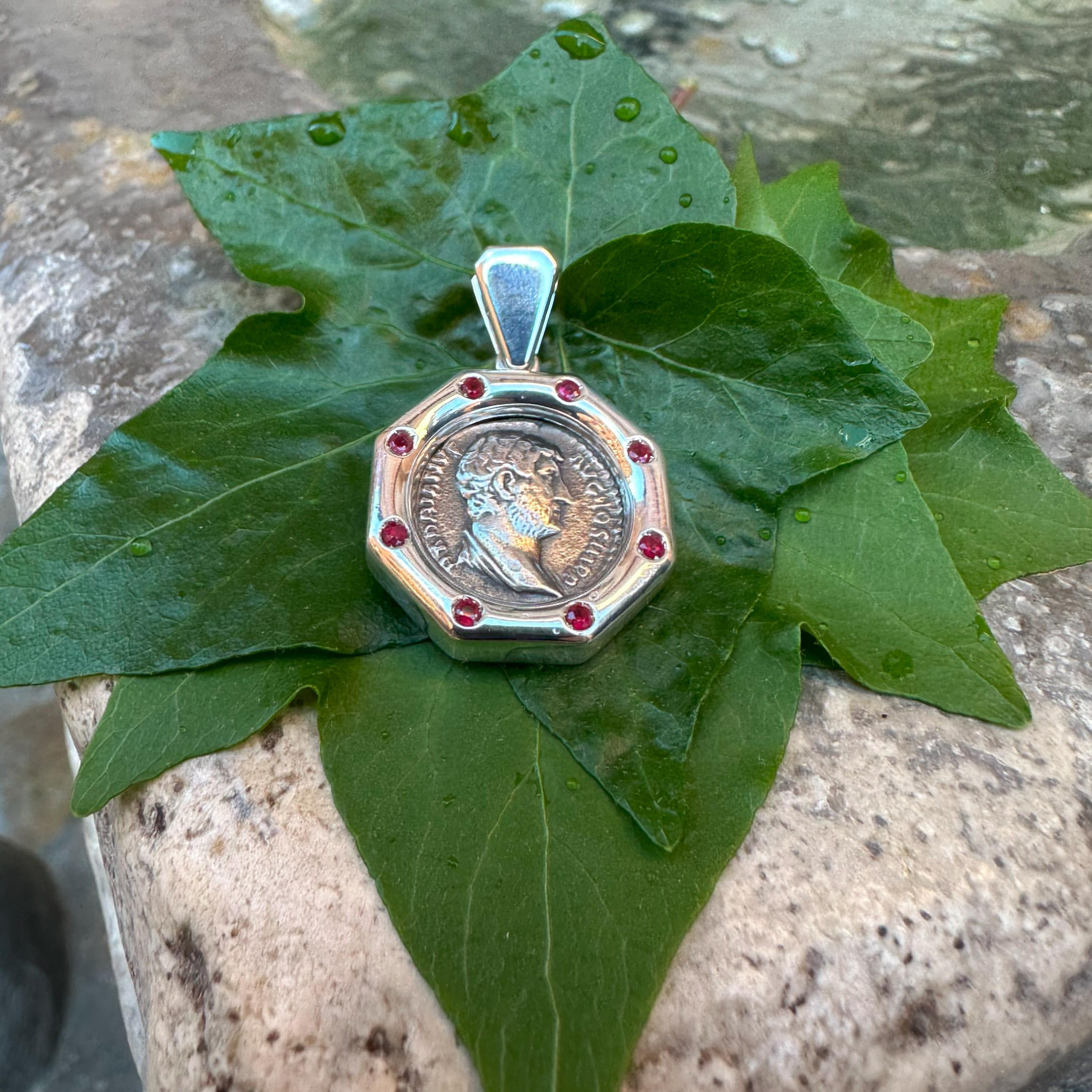 Ce pendentif en argent sterling renferme une authentique pièce de monnaie romaine datant du IIe siècle ADS, représentant l'empereur Hadrien, entourée de 8 rubis d'une valeur totale de 0,60 KT. Le revers représente la déesse Fides, personnification