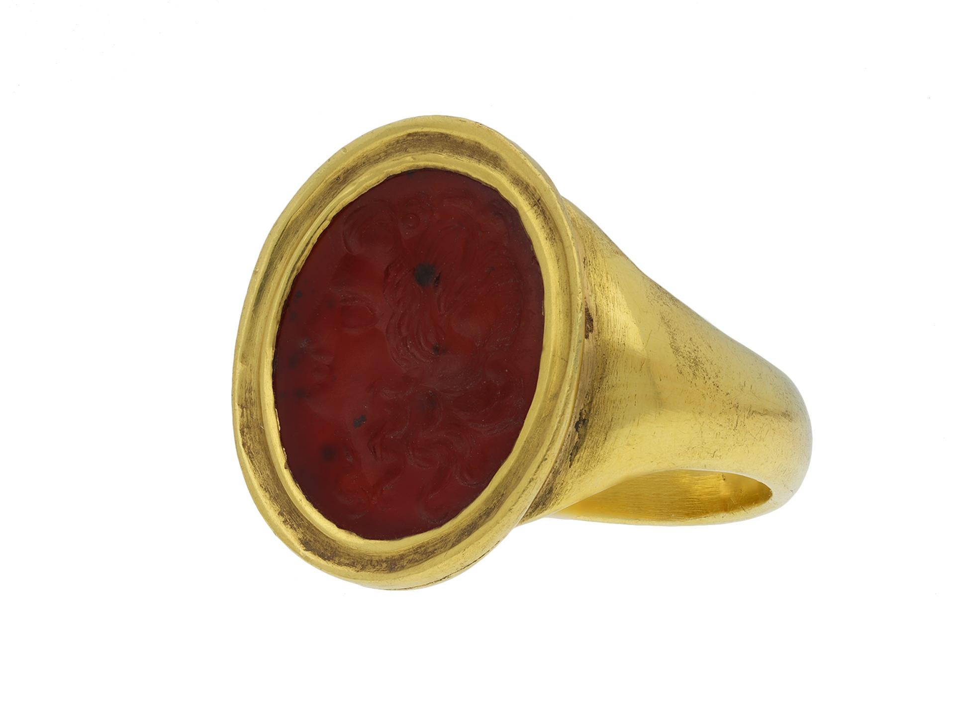 Ancient Roman cornelian intaglio of Apollo circa 200 AD ring. Set to centre with an orange cornelian intaglio of the Greco-Roman god Apollo, circa 200 AD, in a closed back Roman set setting featuring an intricately carved profile bust of Apollo,