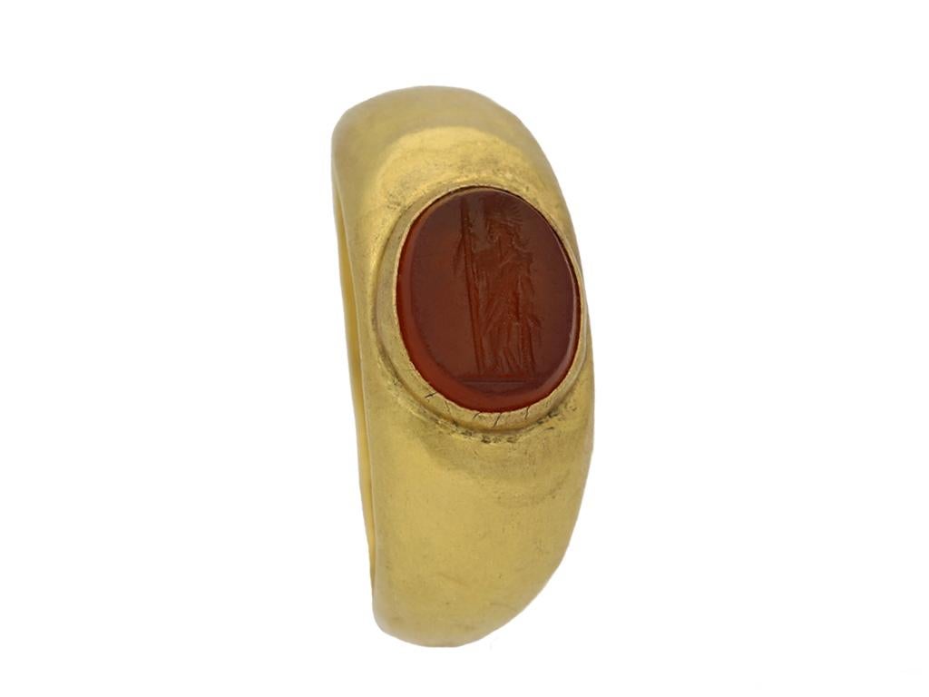 Ancient Roman cornelian signet ring with engraving of Mars. Set with one central oval cornelian intaglio in a closed back rubover setting featuring an engraved full length profile of the ancient Roman god Mars, with polished borders and closed