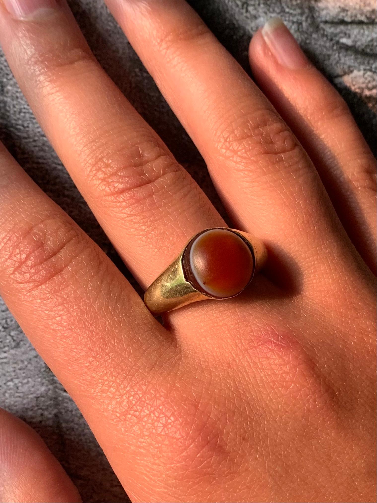 A Roman gold and banded agate amulet ring 
Circa 3rd Century A.D.
The circular banded agate cabochon in the shape of an eye meant to protect the wearer, in a period high carat gold setting. Both the agate and the gold showing age appropriate wear.