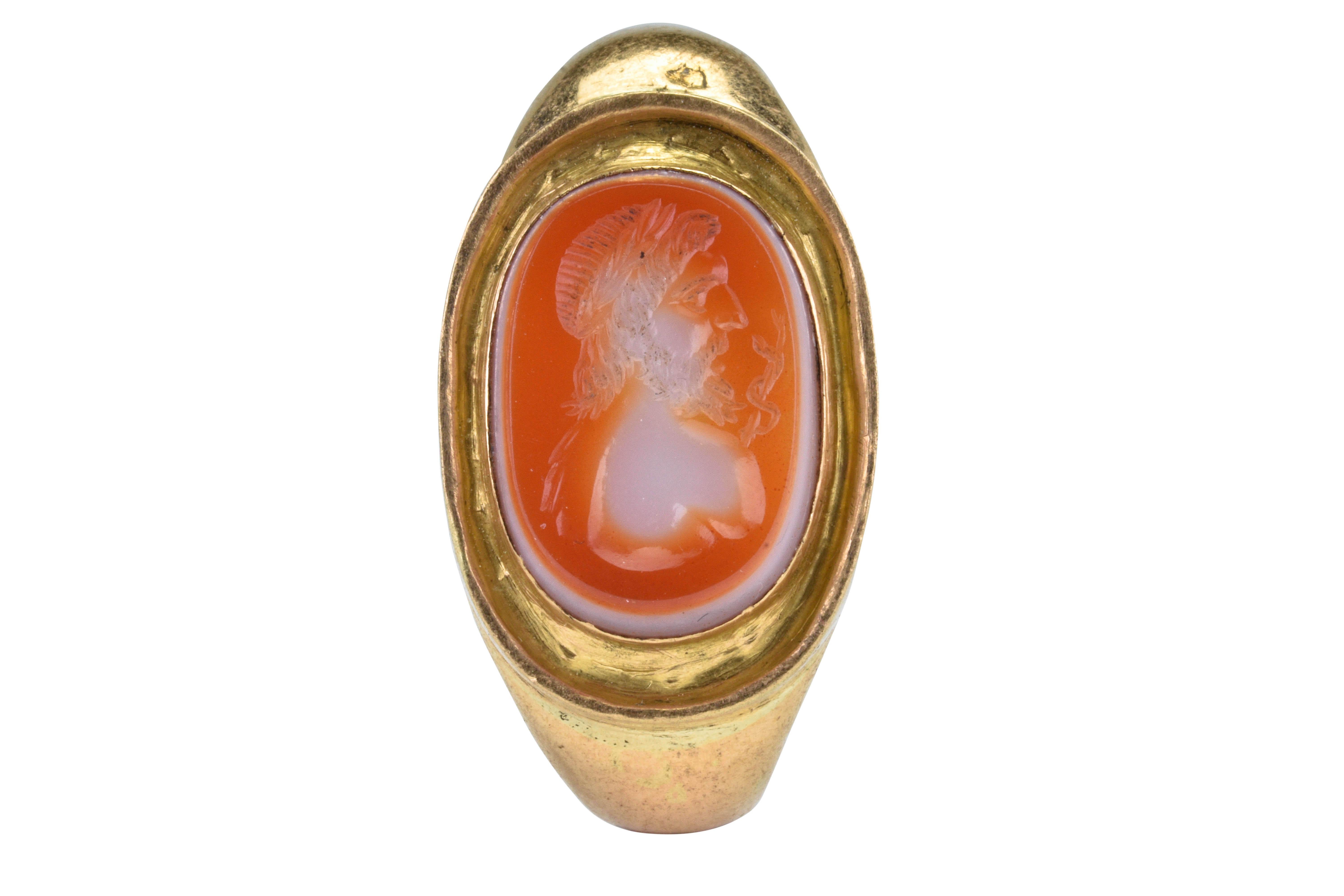 Antiker römischer Gold-Intaglio-Siegelring mit Asklepios

Ca. 100-300 N. CHR

Ein antiker römischer Goldfingerring mit einem D-förmigen Ring, der in eine ovale Lünette übergeht, die eine Steinintaglierung enthält, die eine Büste des Gottes Asklepios