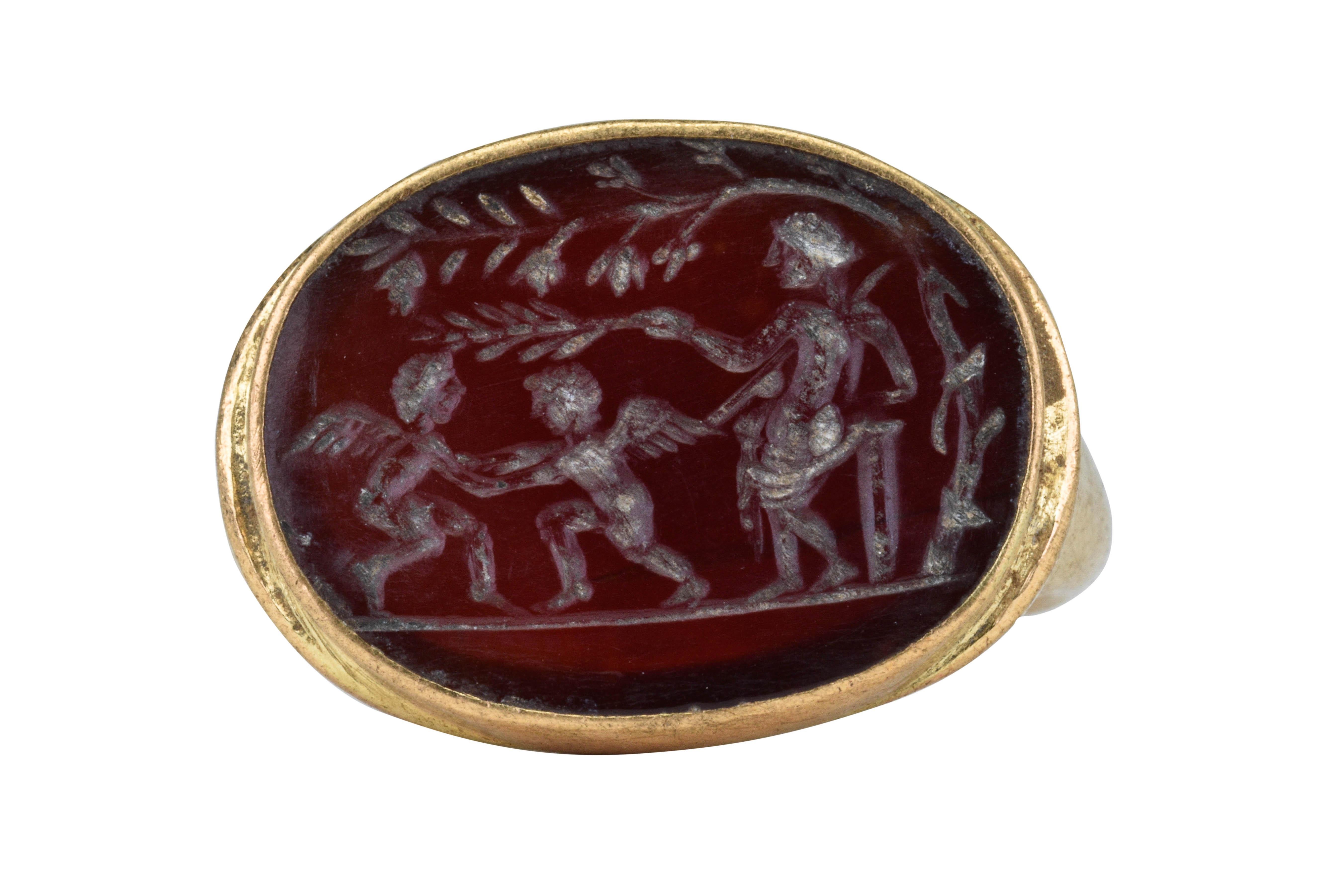Ancient Roman Gold Intaglio Signet Ring with Venus and Two Fighting Cupids

Ca. 100-300 AD 

An Ancient Roman gold signet ring composed of a carinated-section round hoop rising to a large, oval bezel containing a carnelian intaglio engraved with a