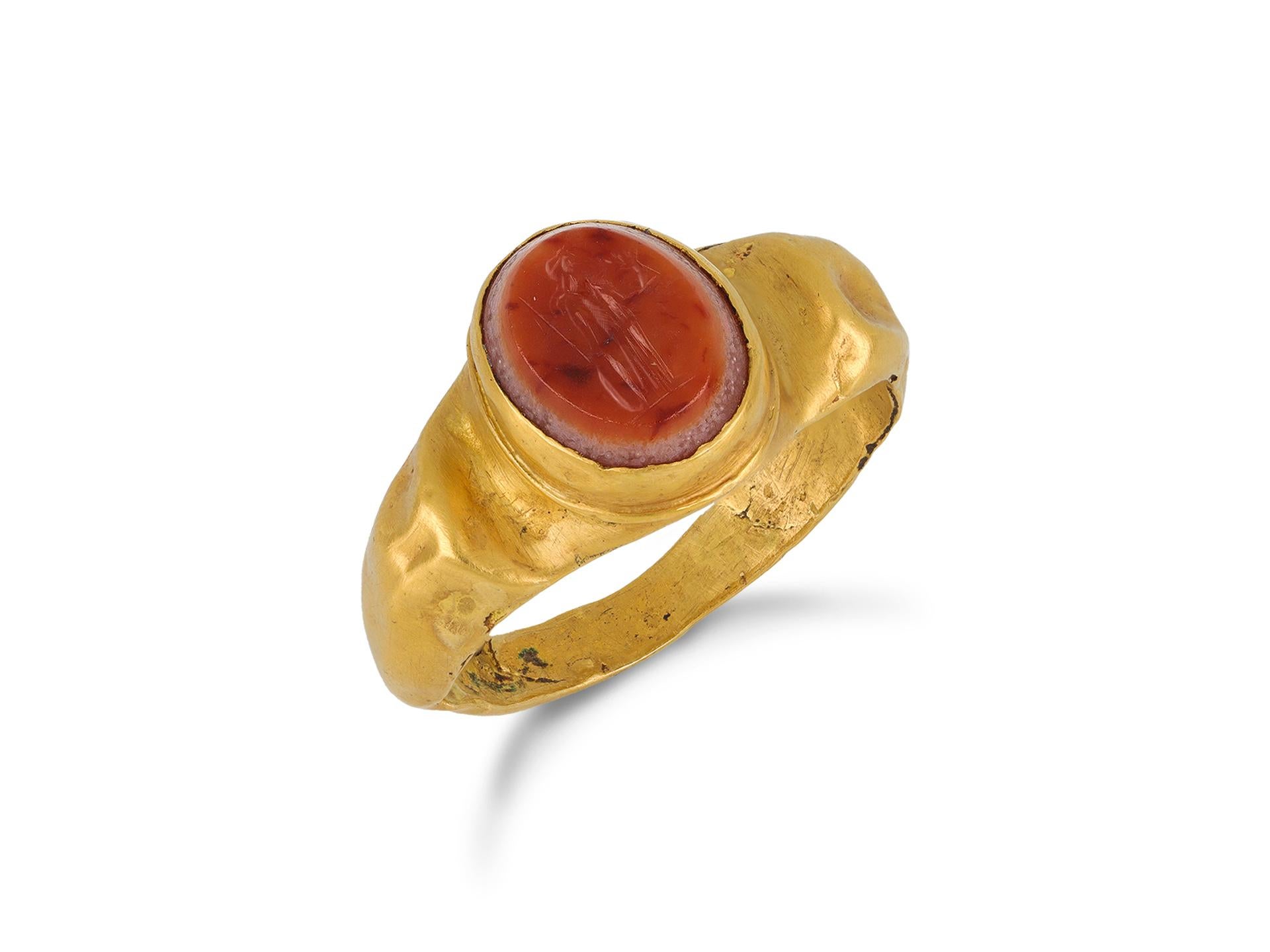 Ancient Roman gold ring with agate intaglio of Minerva. Set with an oval banded agate intaglio to centre of the standing goddess Minerva with long robes and helmet, holding a winged statue of Victory, a spear and a shield, in a closed back Roman set