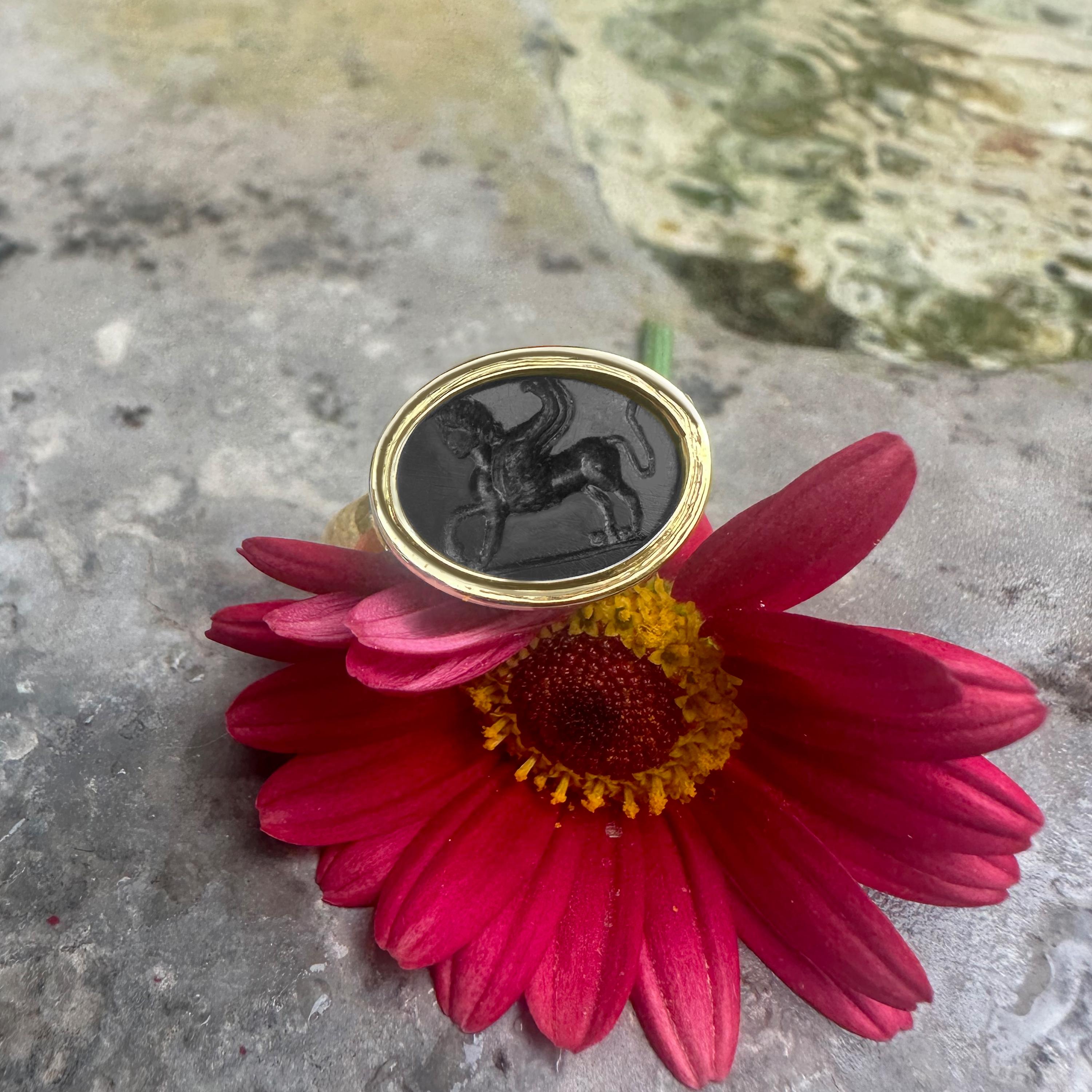 Crafted by our skilled goldsmiths, this 18 Kt gold ring features an authentic Roman onyx from the 1st-2nd century AD, adorned with a captivating depiction of a Sphinx. Positioned amidst realms of both humanity and fantastical creatures, the