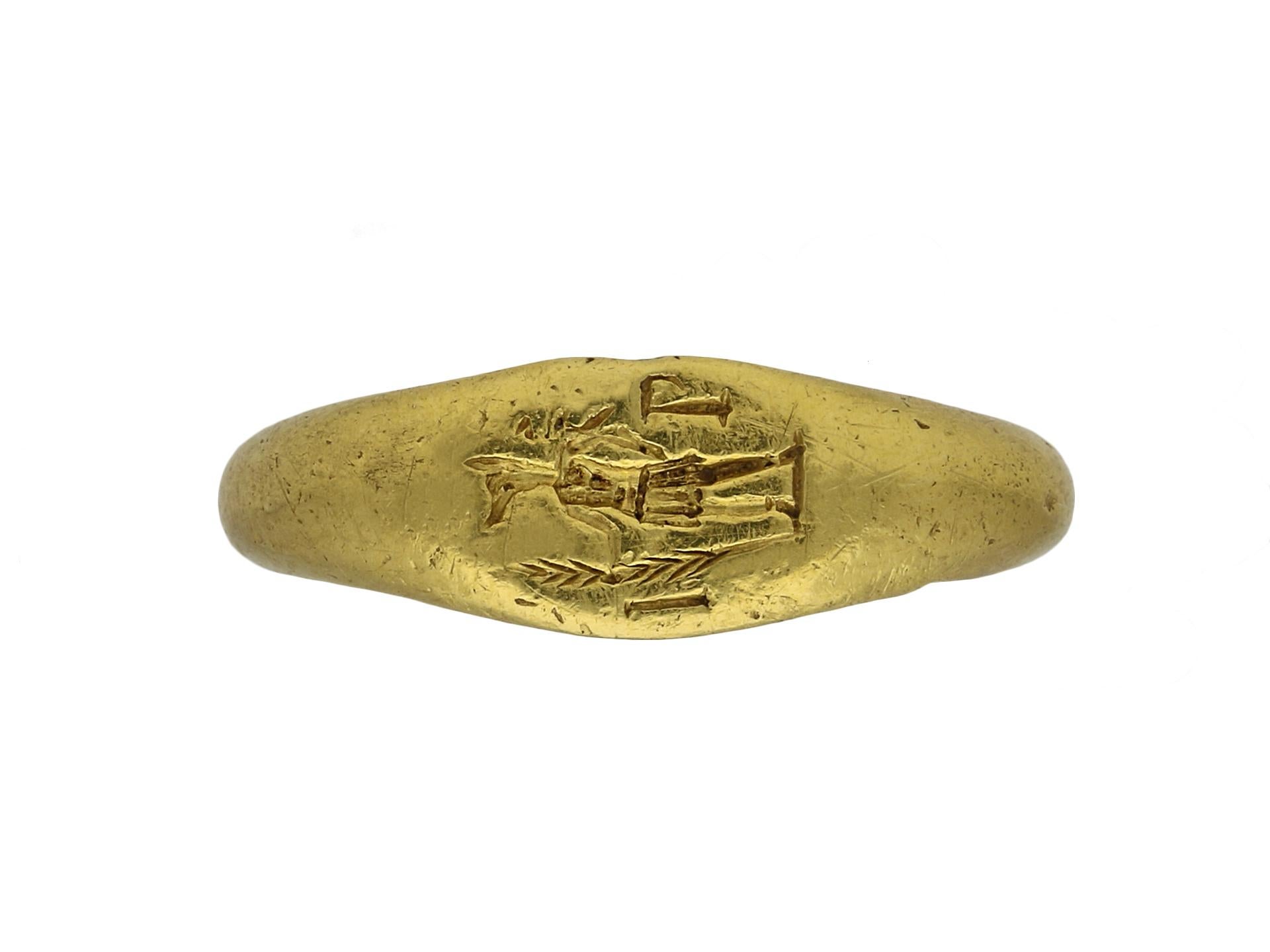 Ancient Roman signet ring.  A yellow gold ring composed of an oval bezel engraved with a full-length figure of Hermanubis in Roman dress holding a branch/staff, and flanked by the letters I and P, with integrated conforming shoulders flowing through