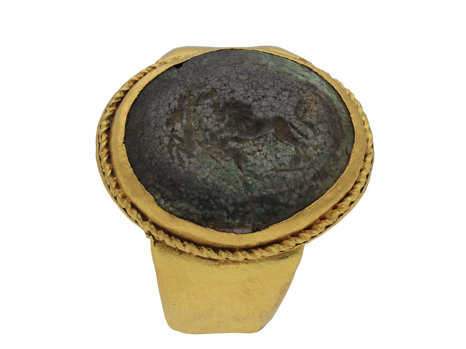 Ancient Roman signet ring. Set with one central oval hardstone intaglio in a closed back Roman set setting engraved with a lion catching a gazelle, to an oval signet featuring a twisted wire border and polished edges, leading to trumpeting shoulders