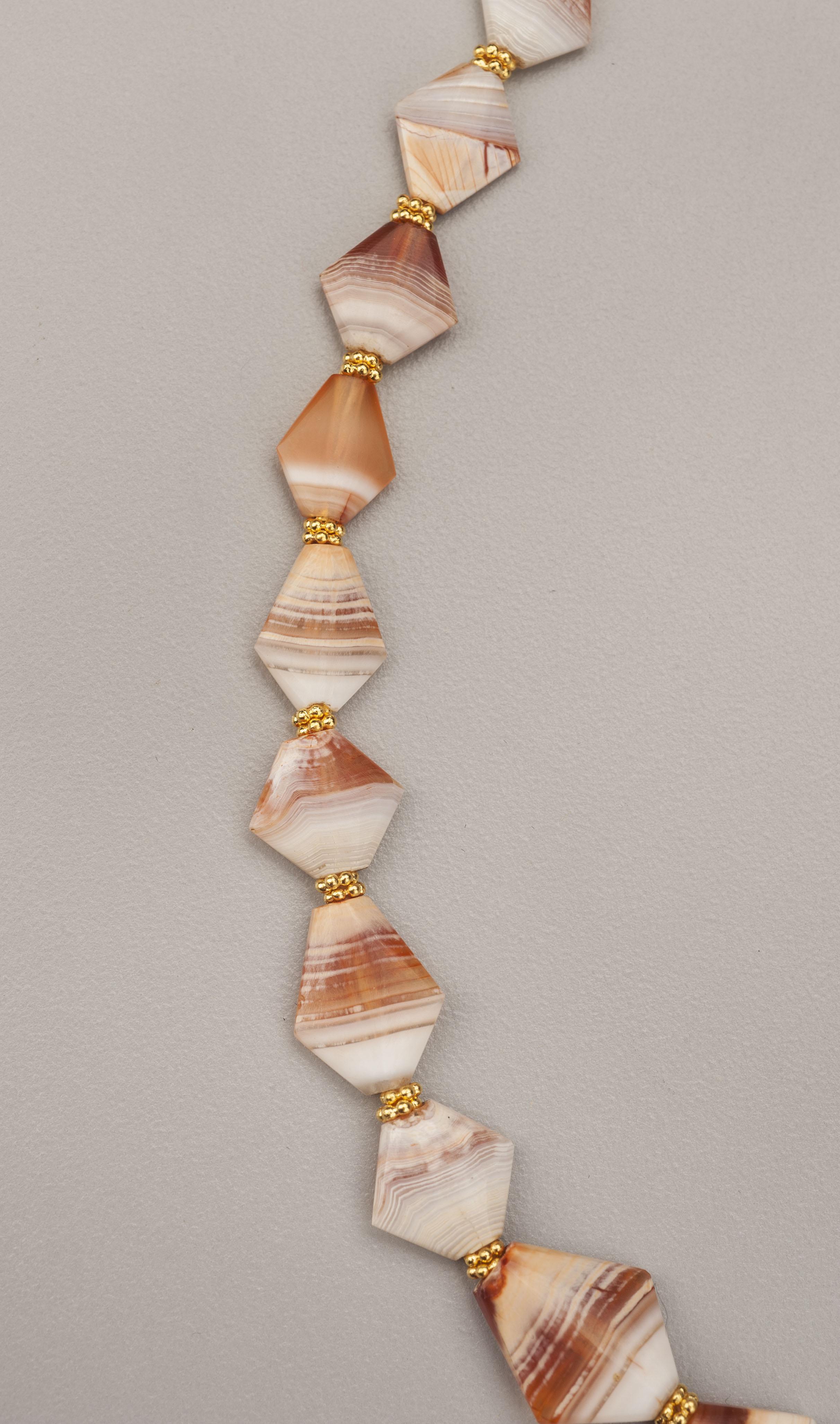 Thirty-five rhomboid tabular sardonyx/agate beads alternating with pairs of granulated gold ring beads. Gold beading tips and a hook and eye clasp complete the necklace. The gold is 24k. The agate is composed of transparent and opaque white quartz