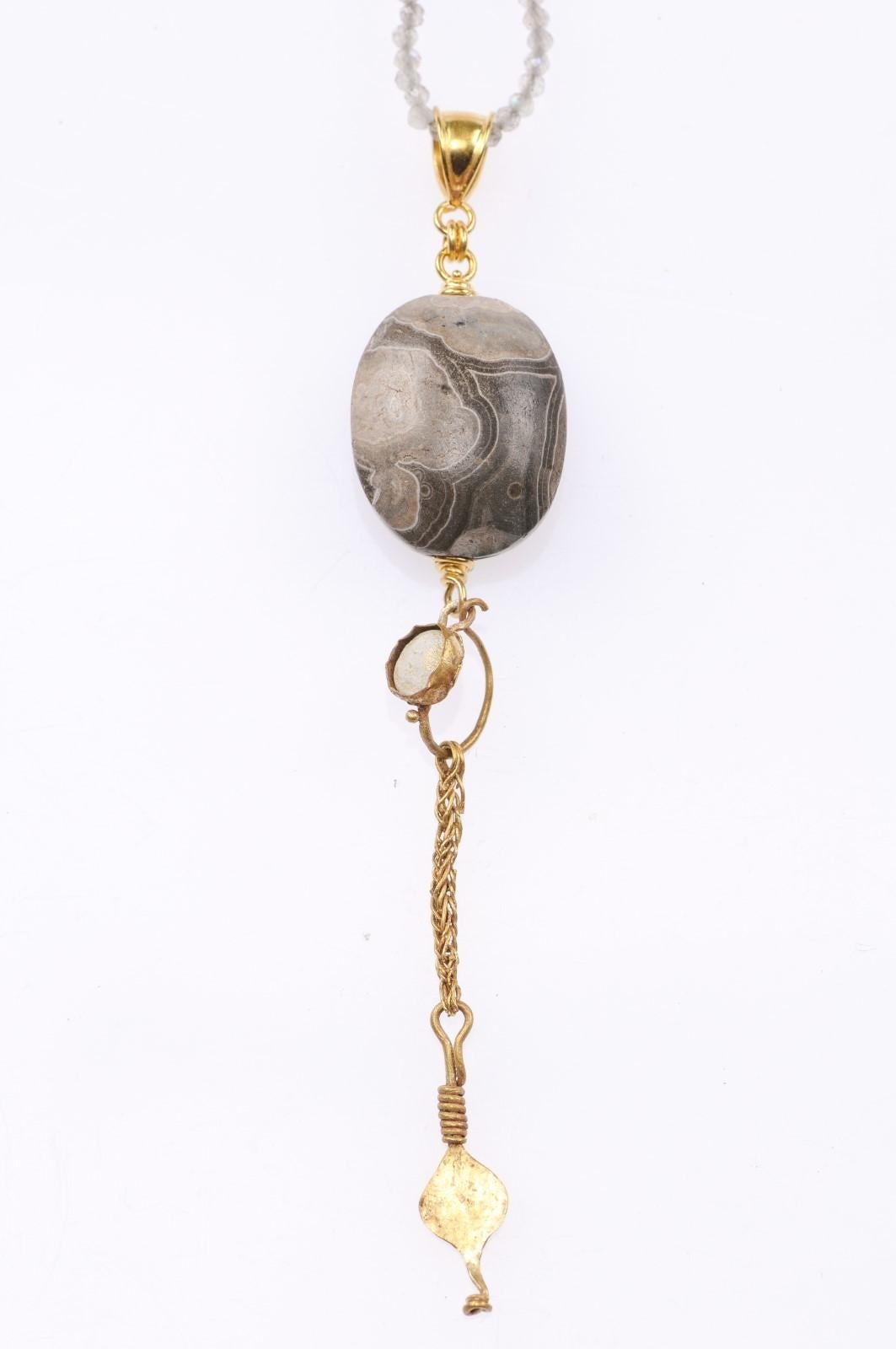 Un scarabée d'agate sumérien (vers 2000 avant J.-C.) est serti dans un pendentif en or 21 carats, avec une boucle d'oreille romaine en or avec verre (vers le 1er ou le 3e siècle avant J.-C.), et un anneau en or 21 carats. Les mesures sont les