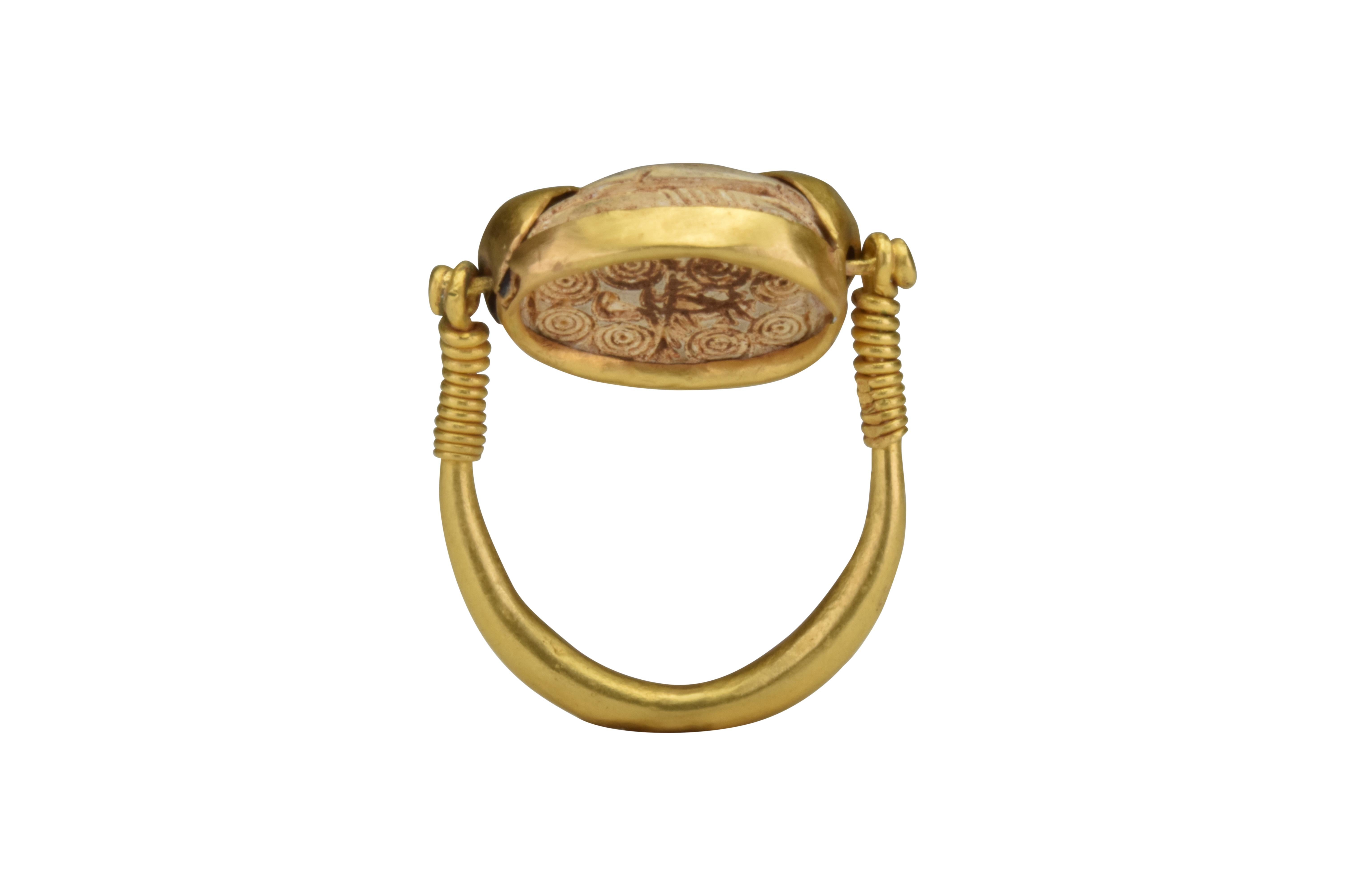 Ancient Signet Egyptian Gold Scarab Ring 
Ca. 500 BC
A museum-quality scarab ring in common fashion on top but the base when swivelled reveals a field of numerous circles.

Size: D: 10 1/4mm / US: 10.5 / UK: V; 9.71g 

Provenance: Private London