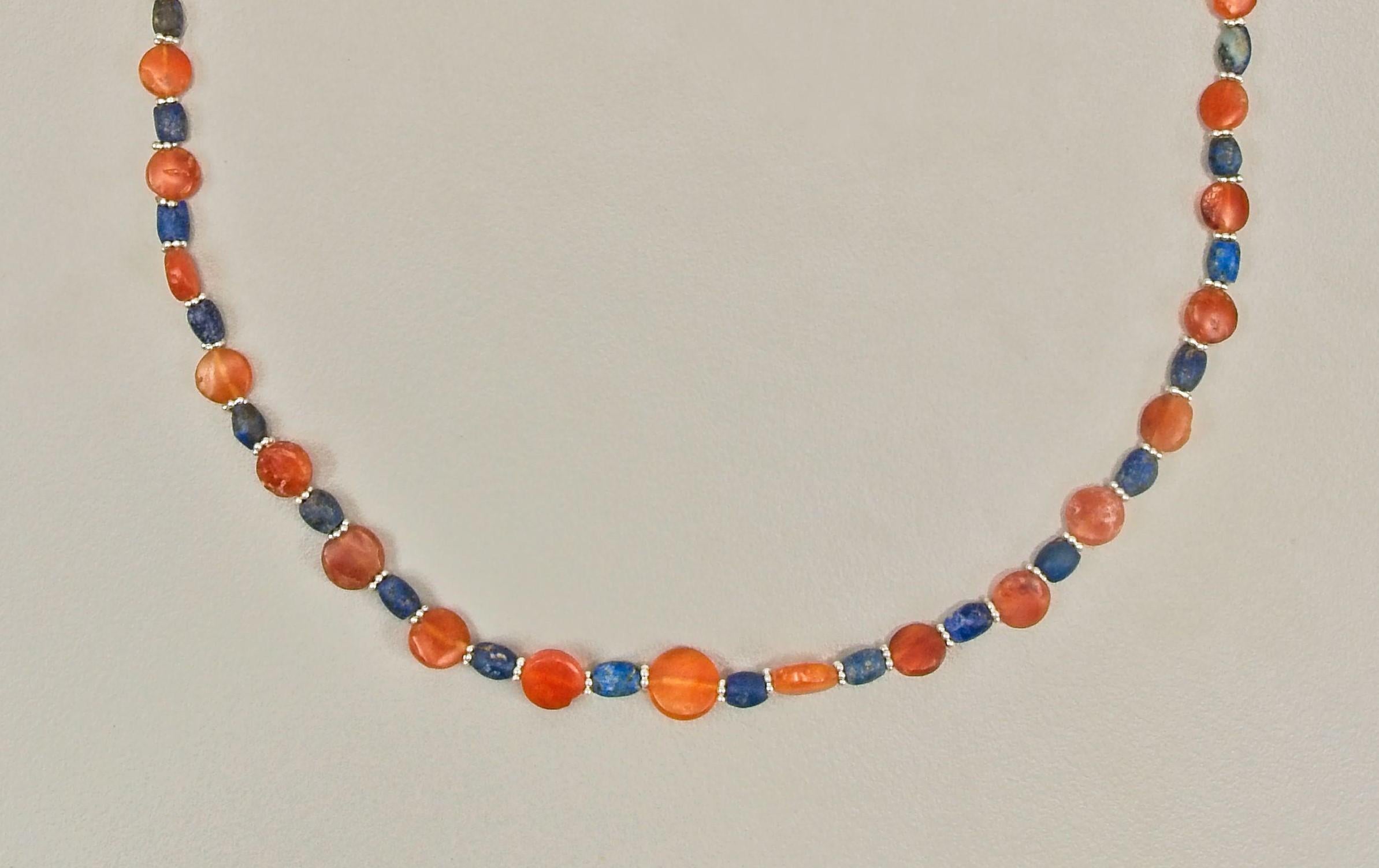 Thirty-one tabular carnelian beads alternating with thirty-two barrel shaped lapis lazuli beads. There are sixty-two silver ring beads in the necklace; they occupy the spaces between each of the stones beads. Each is composed of five granules fused