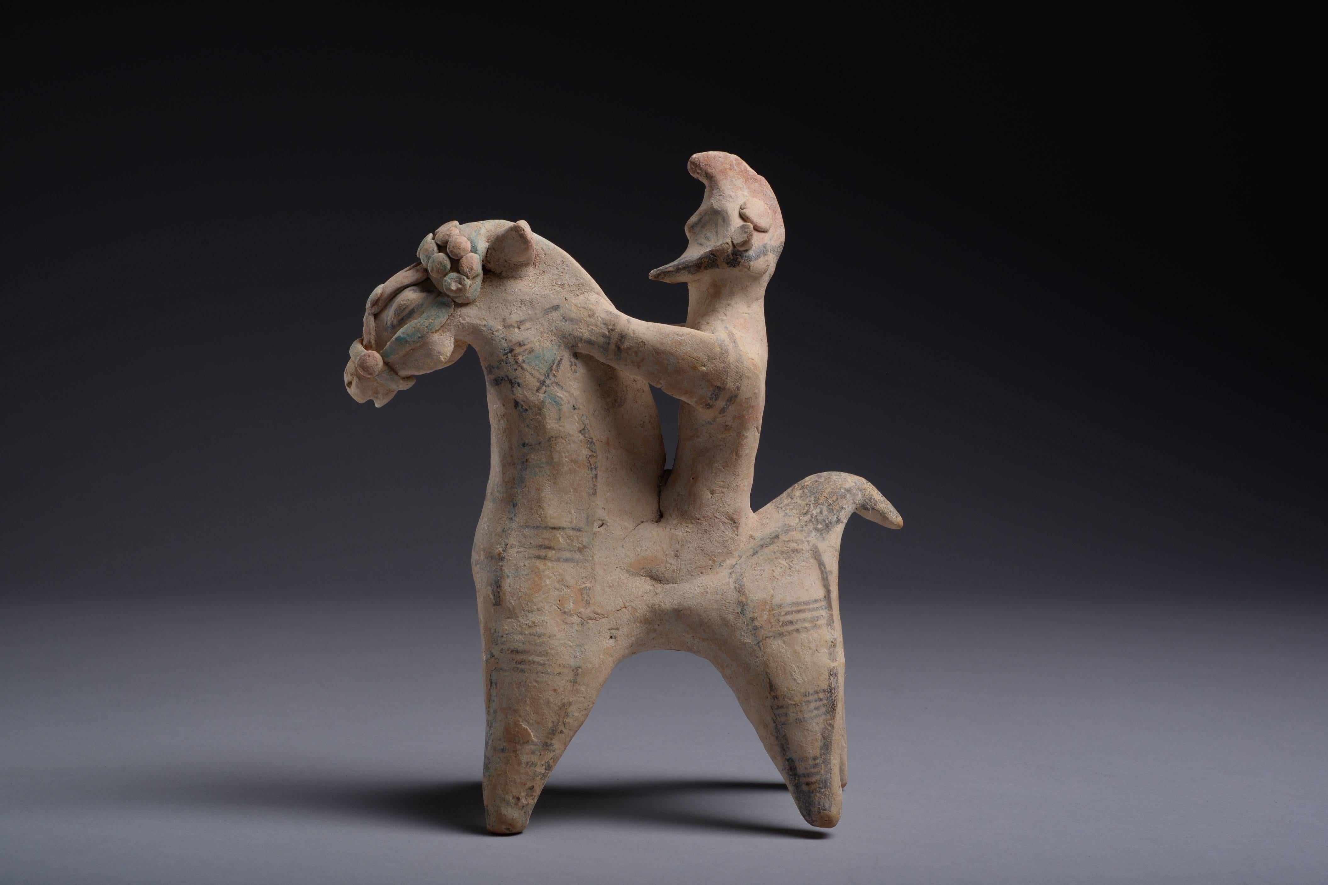 A terracotta model of a warrior on horseback from Cyprus, dating to the Cypro-Archaic period, circa 7th-6th century BC.

The horse standing with a raised head, its bridle painted in red and green. The rider holding onto the horse’s neck with both