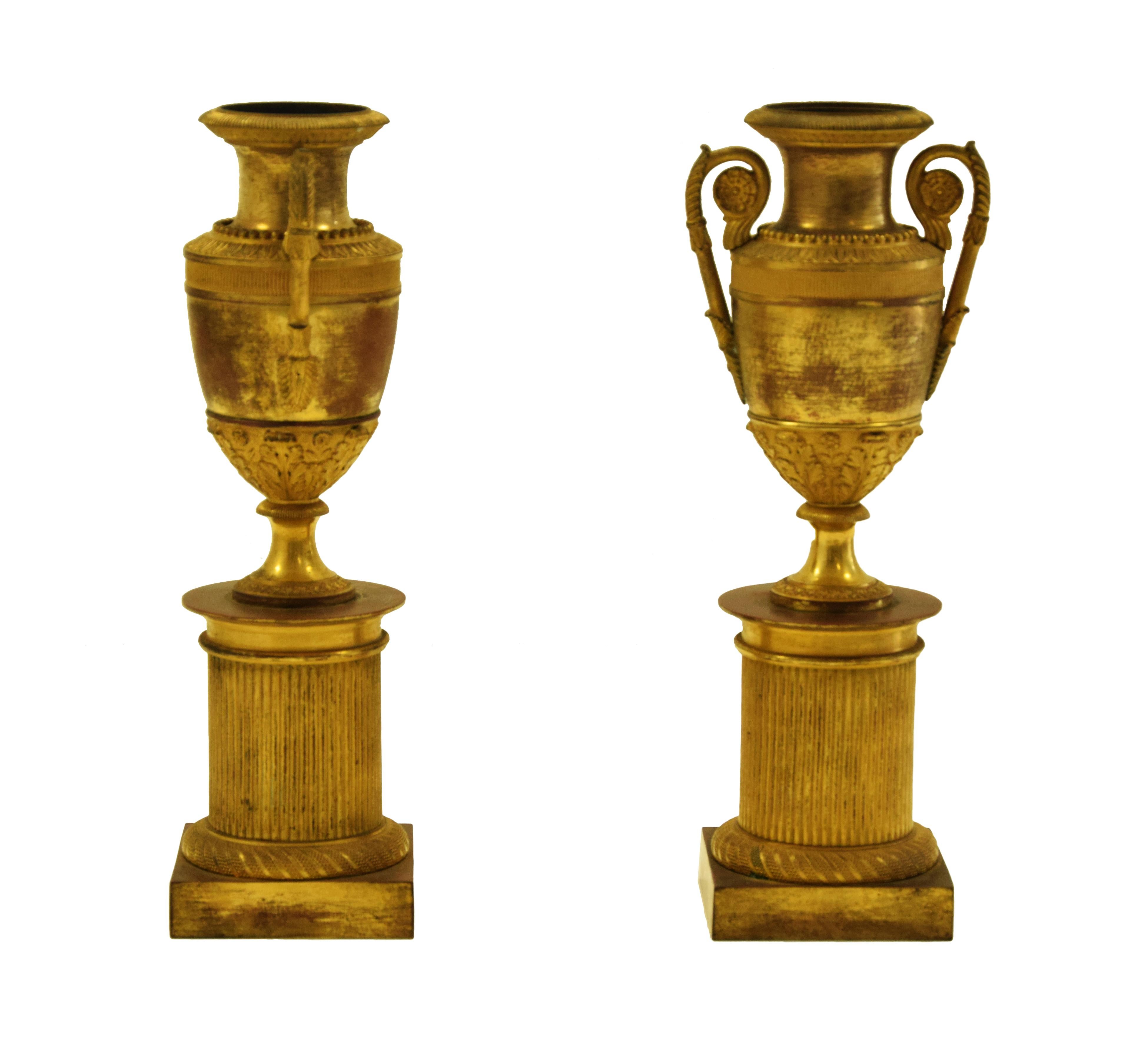 Das Vasenpaar auf Sockel ist ein originelles Dekorationsobjekt aus der zweiten Hälfte des 19. Jahrhunderts.

Original vergoldete Bronze.

Antike Goldpatina.

Neuwertiger Zustand.

Schönes Paar Vasen mit einem zylindrischen geriffelten Basis