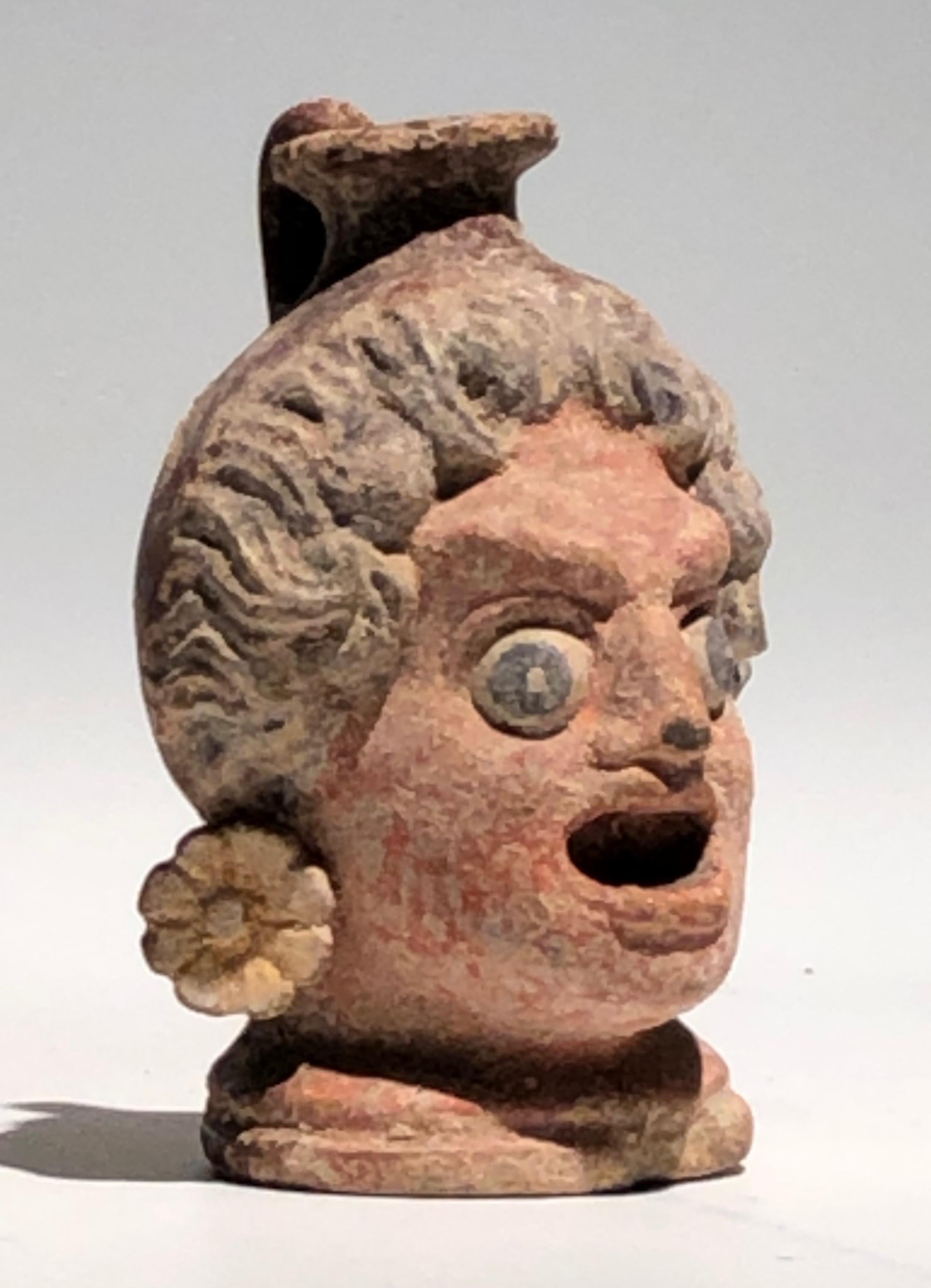 Western Greek polychrome head vase of an actor with a face of a dramatic theatre mask, wearing gilded earrings, circa 4th century BC.
The vase, actually a miniature lekythos with a handle at the back of the head, would have contained aetheric oils