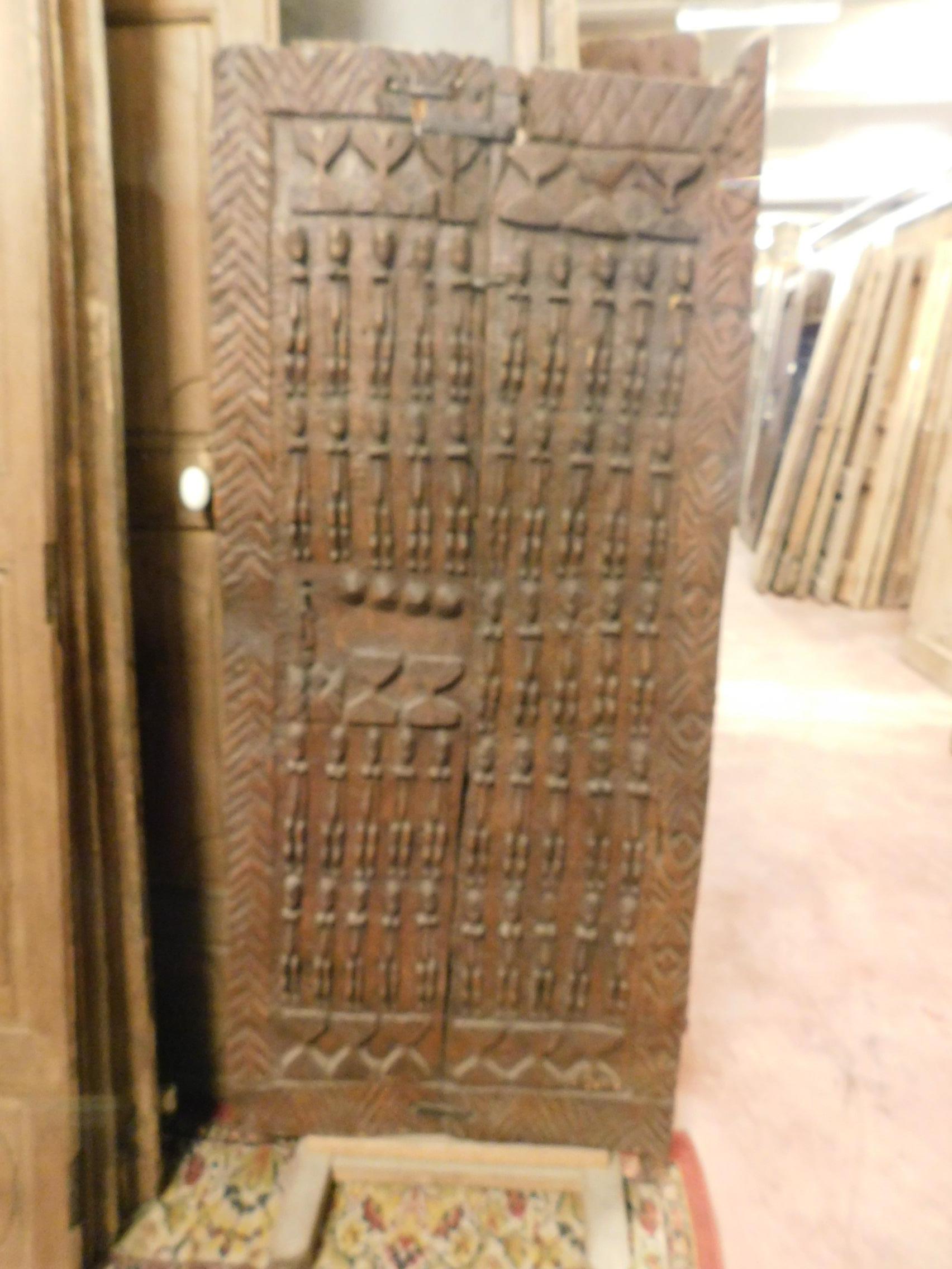 Ancient wooden door of African tribal chieftain, carved with images of outdated enemies to become chief, is small because the subjects had to bow to him to enter his house, very special and rare, usable also as a decorative panel, all carved by hand