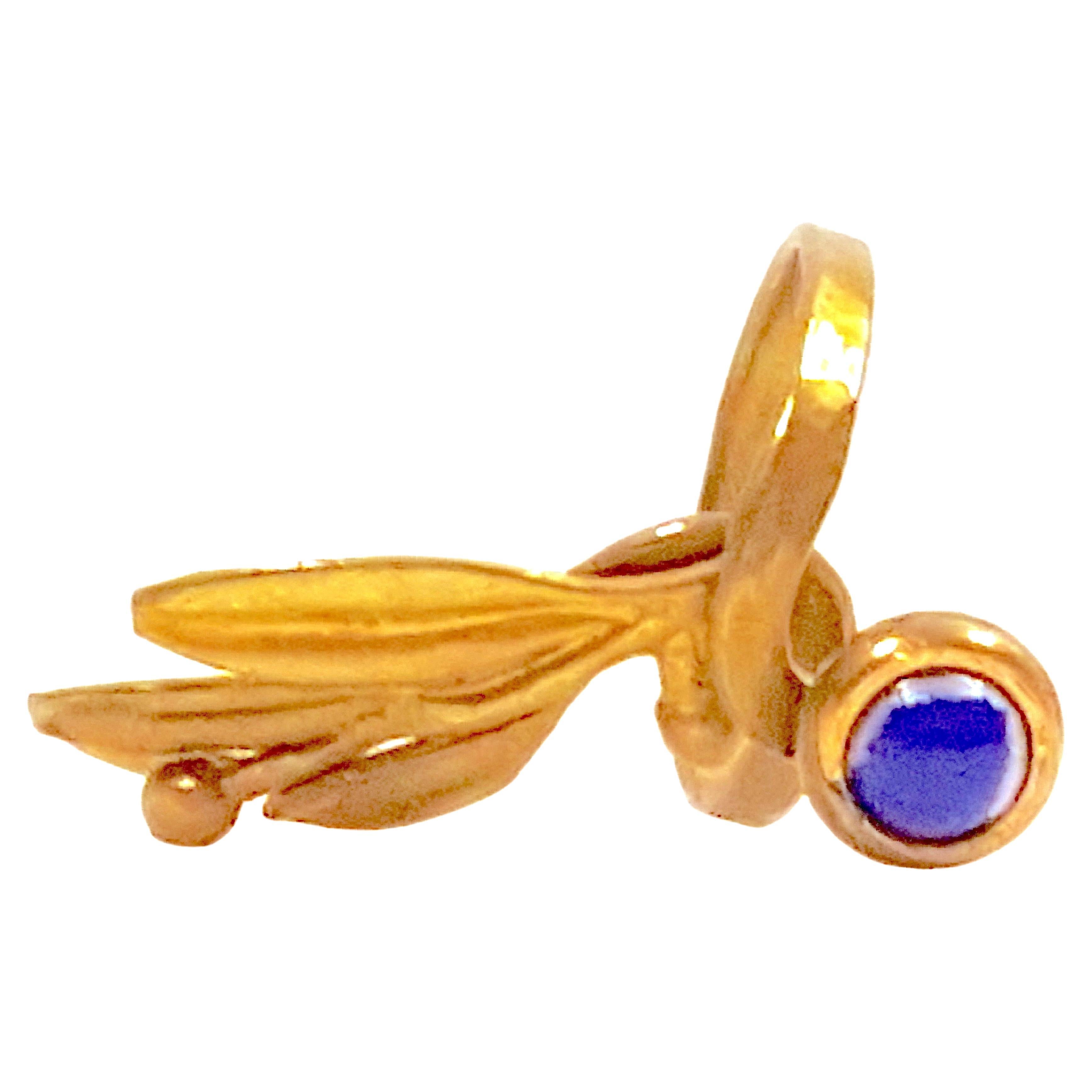 Found in Greece, this ancient style gold-smithed sculptural open-work ring features at its raised end a bezel-set lapis cabochon, while the other end of the by-pass band below is shaped like a sprig of laurel leaves or miniature olive branch. While