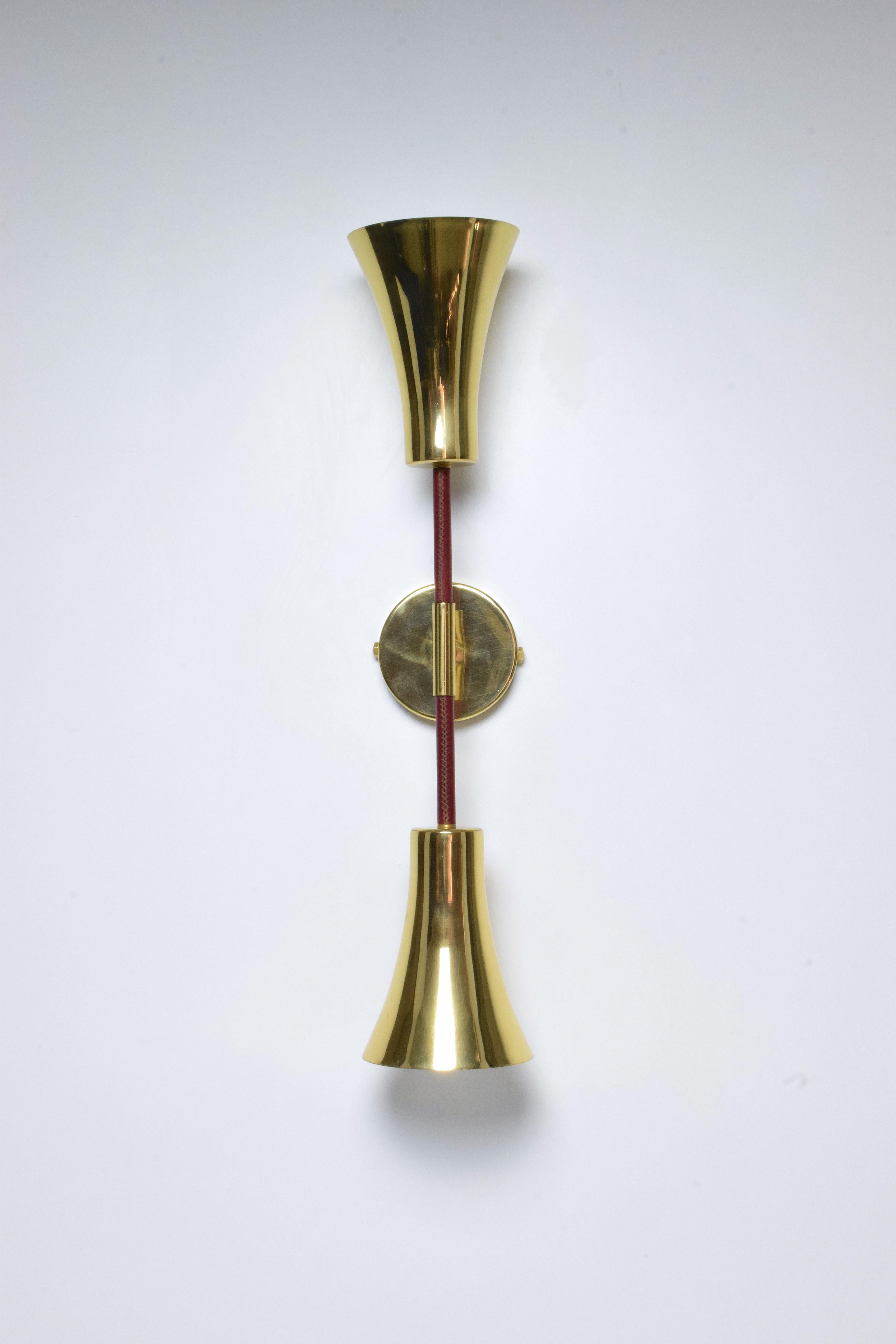 Contemporary modern handcrafted wall lamp fixture or sconce, composed of a double gold polished solid brass light shades and a structure and a leather sheathed detail on both ends of the stems hand sewn by artisan saddlers. 
 
21st century