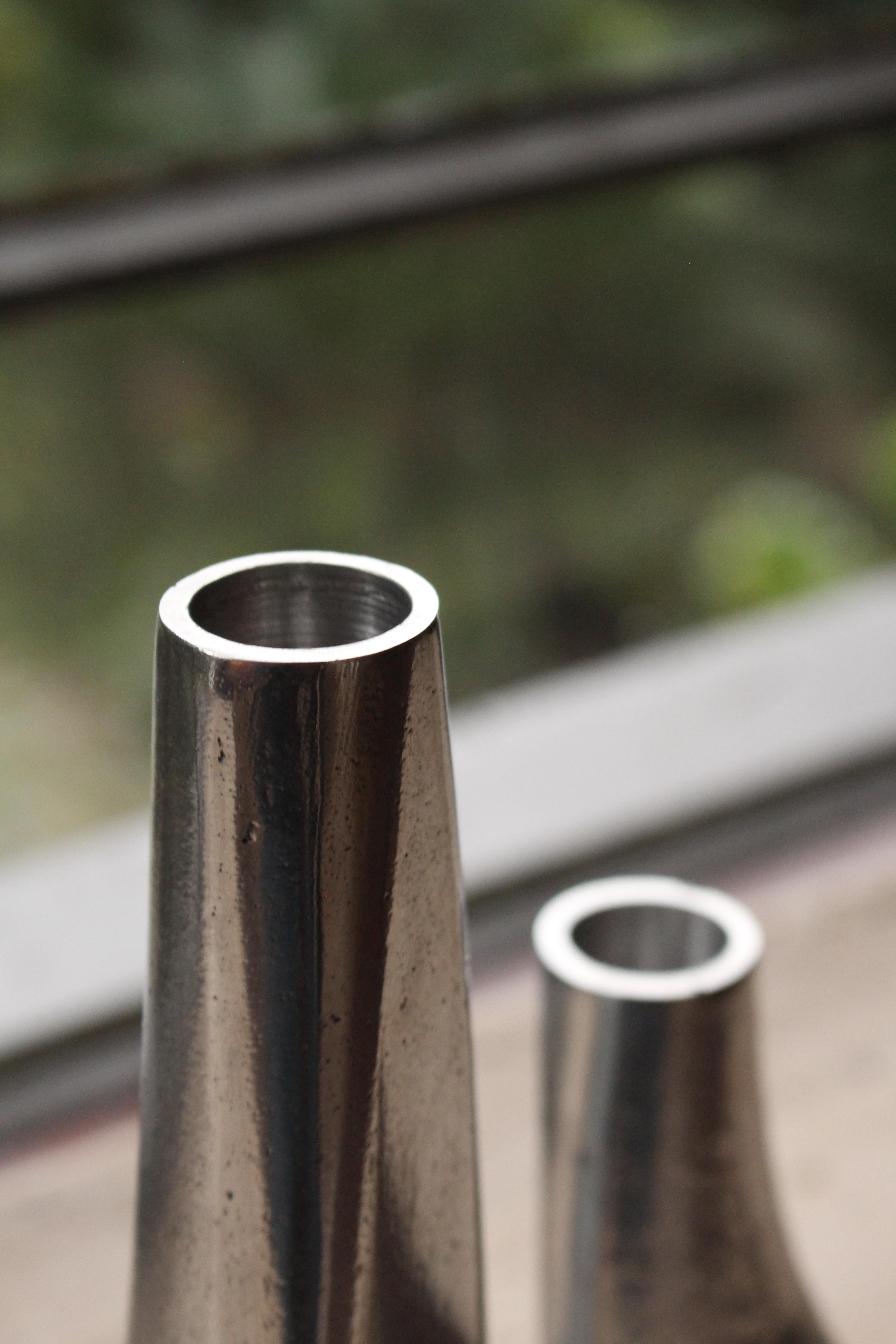 Âncora, entworfen von Christian Haas, ist ein Kerzenständer aus Aluminium-Sandguss. Die Form mit zwei Hohlräumen ermöglicht es, den Kerzenhalter mit einer einfachen Drehung auf zwei Arten zu präsentieren. In einer Position ist die Höhe größer als in