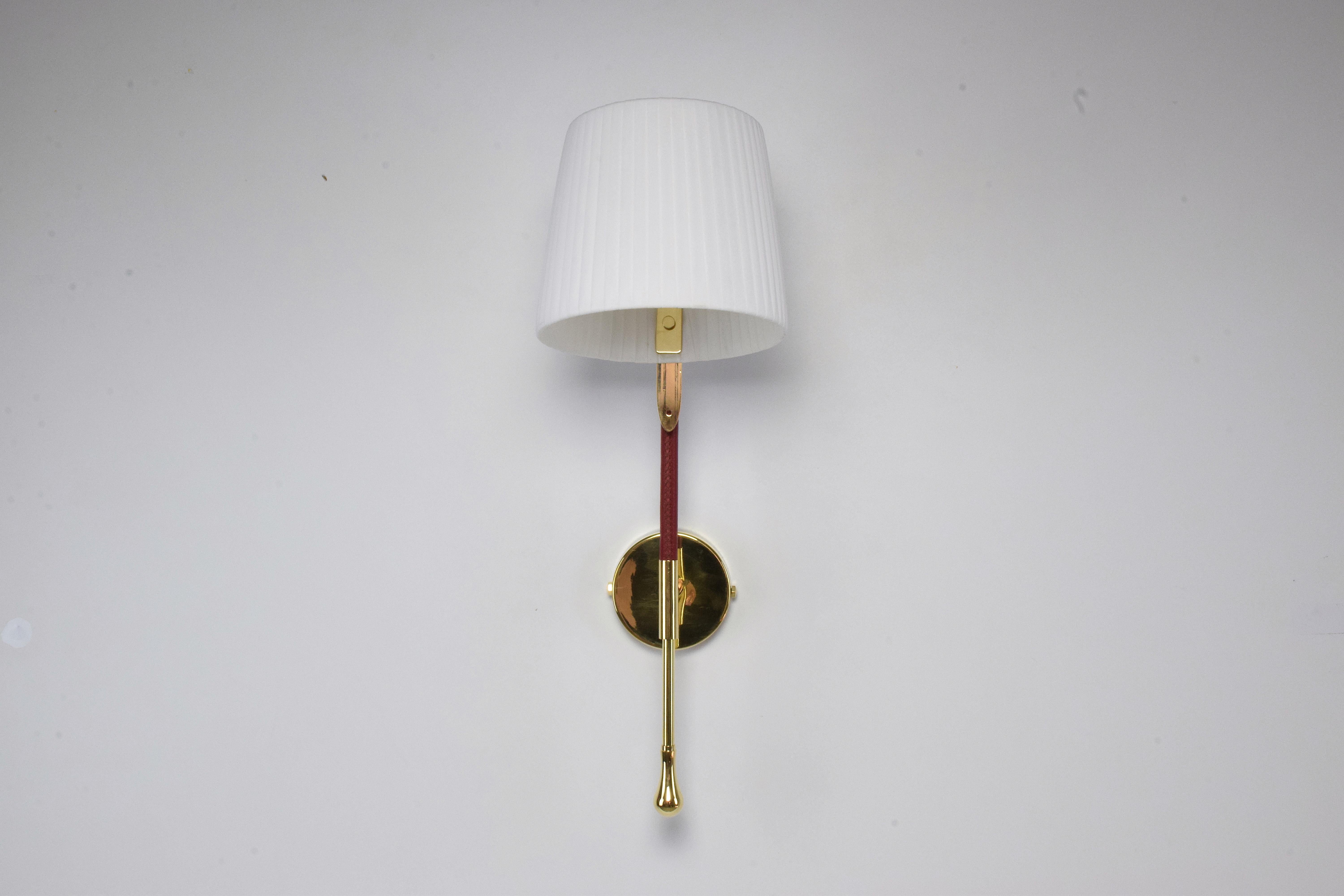 21st century contemporary handcrafted wall lamp fixture or sconce, made of a gold polished brass structure adorned with a brown sheathed leather detail hand sewn by artisan saddle markers, a white soft fabric pleated shade with 90° rotation which is