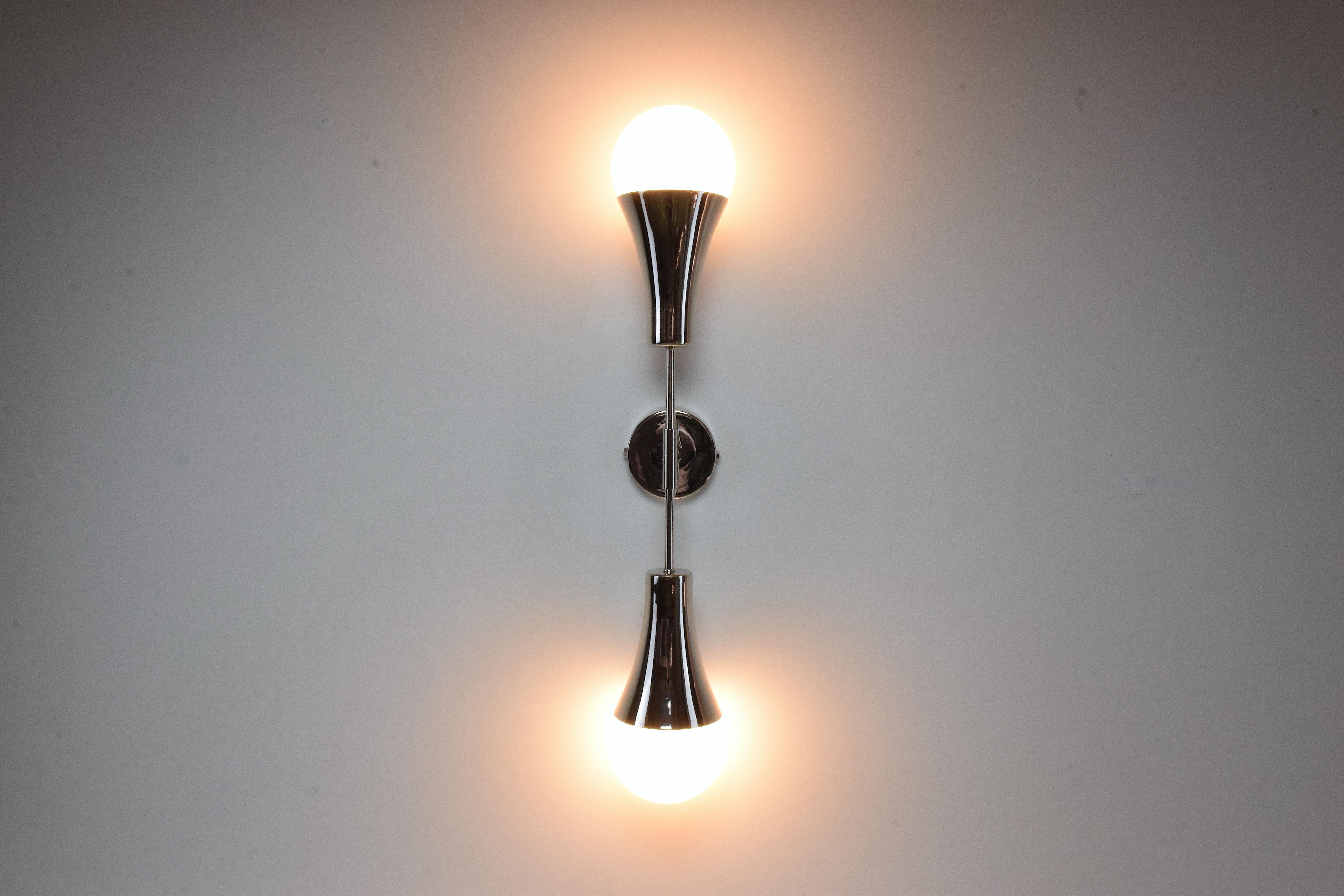 Contemporary modern handcrafted wall lamp fixture or sconce, composed of a double silver nickel plated polished solid brass and opaque glass boule light shades. A leather-sheathed detail on both ends of the stems hand sewn by artisan saddlers is