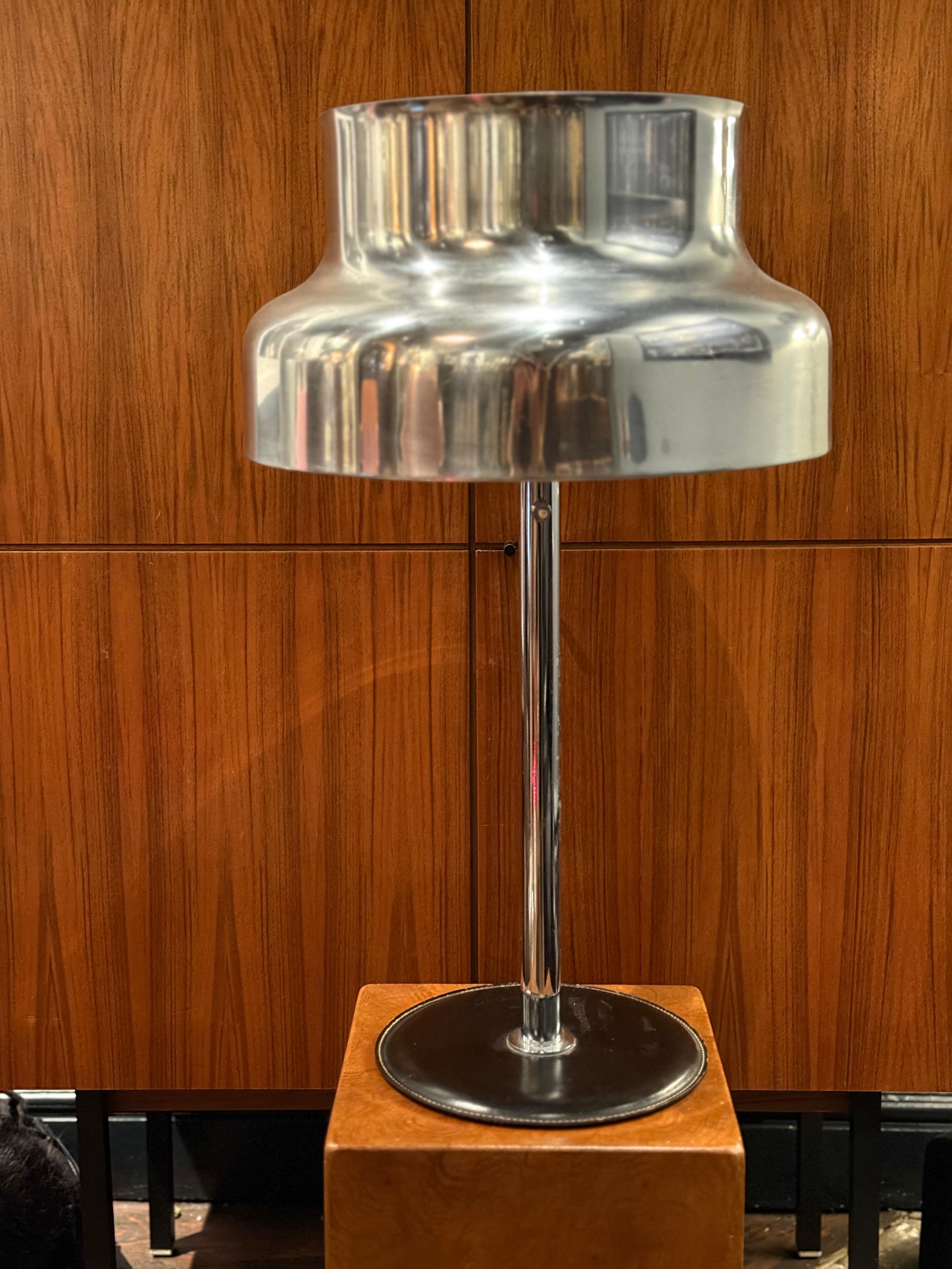 Le grand modèle de la lampe de table Bumling Statement avec un socle recouvert de cuir noir. Fabrication de haute qualité. Le cuir mat contraste avec la surface chromée mate.
Très bon état vintage avec de légers signes d'utilisation, quelques