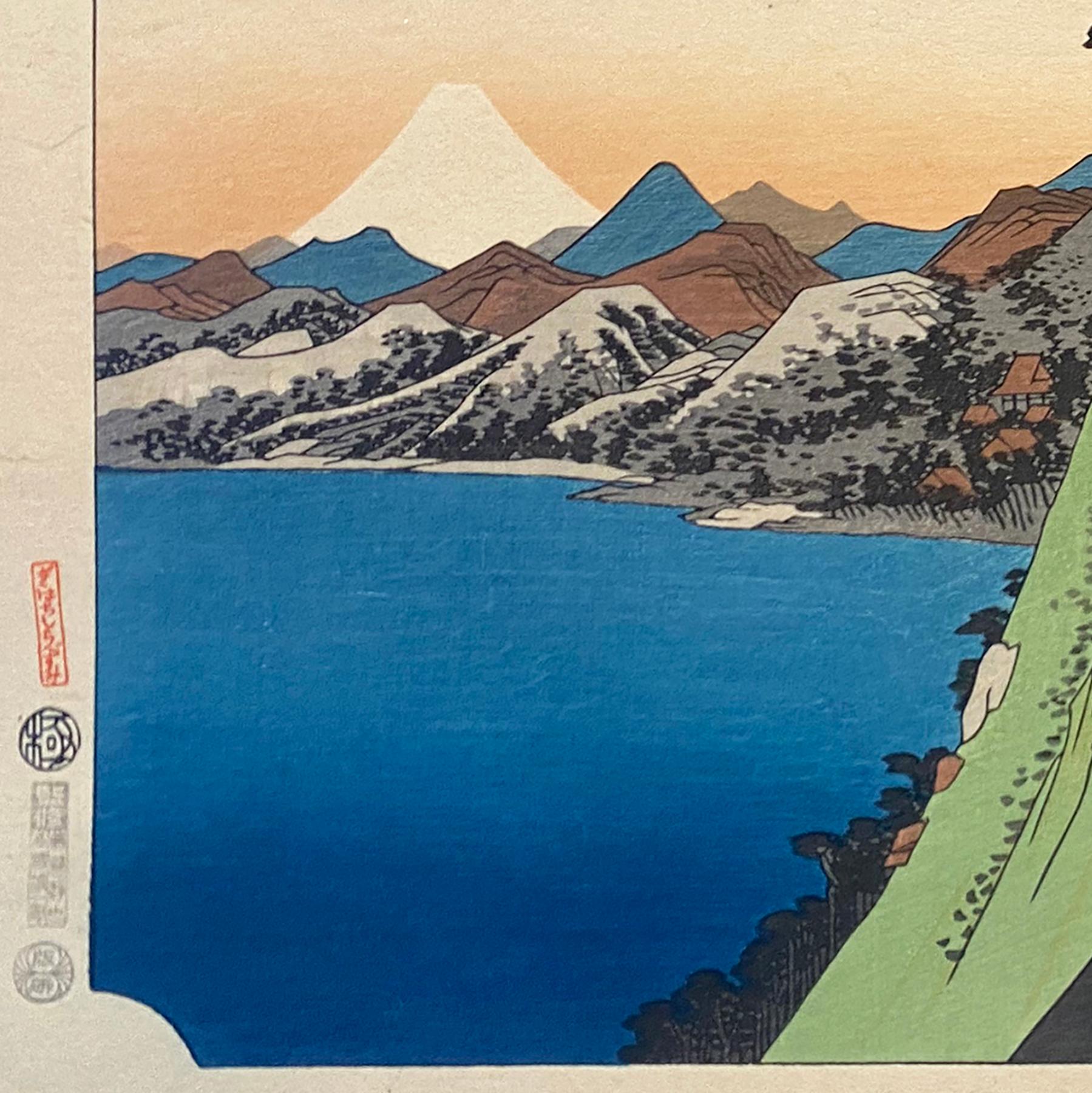 Eine Tusche auf Papier, Nishiki-e- und Yoko-e-Holzschnitt-Landschaft, die einen Blick auf die mit Kiefern bewachsenen Hügel von Hakone mit Blick auf den See und den Berg Fuji in der Ferne zeigt. Signiert in Kanji oben links 