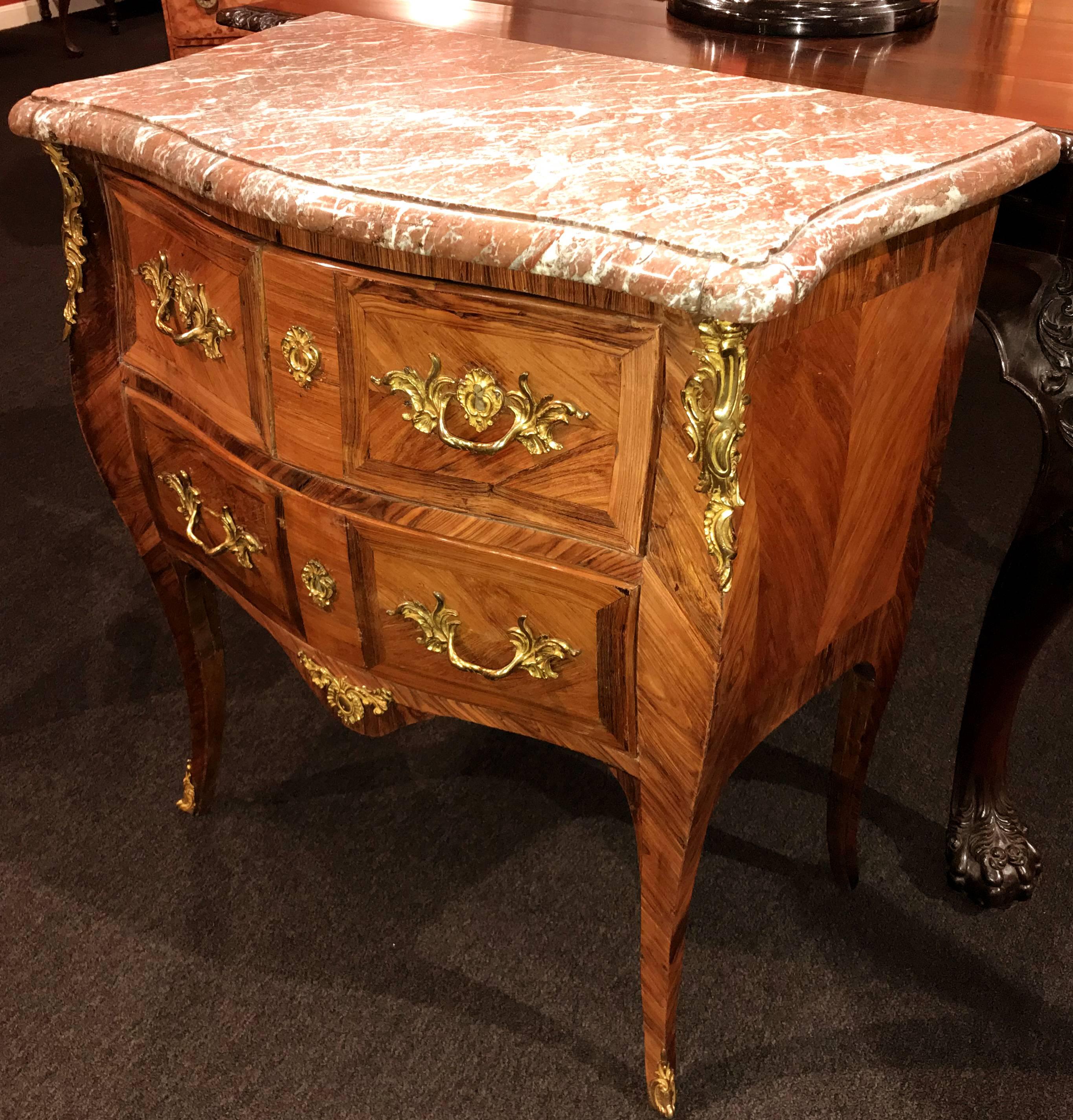 A fine diminutive Louis XV three-drawer commode with Breche d’Alep marble conforming top in shades of pink and grey with molded edge and notched corners, surmounting a case with two fitted drawers over a single long drawer, all with rosewood and
