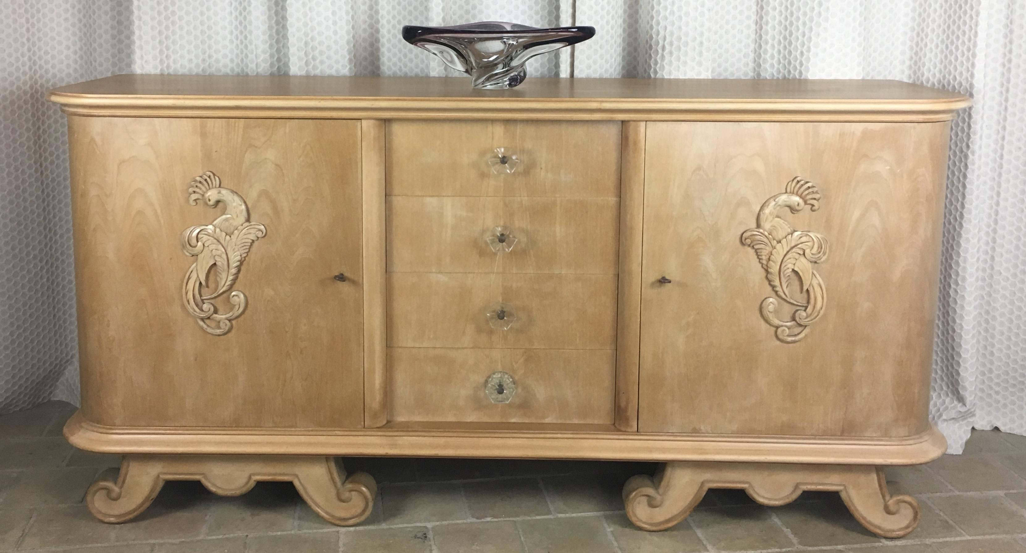 A stunning French mid-century credenza, sideboard or buffet in the style of Andre Arbus made of blonde sycamore with 4 drawers behind two doors having centered hand carved phoenix and trim above scrolled feet, circa 1940s. 

Customization of the