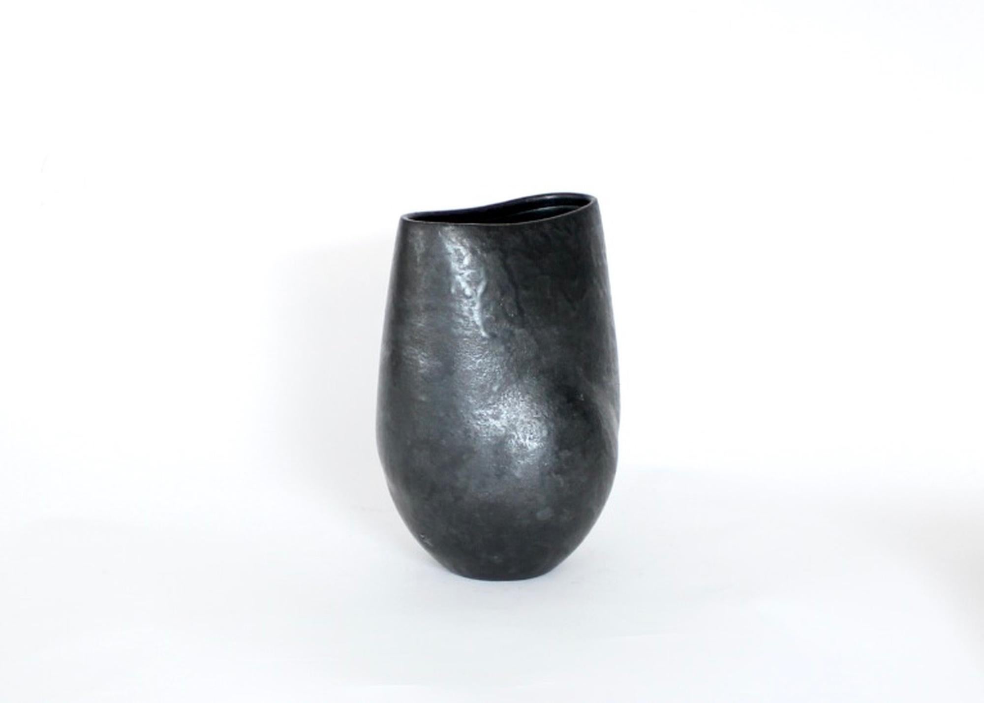 Eine niedrige Keramikvase des französischen Künstlers Andre Bloch. Bloch verwendet einen stark geriffelten Ton und eine tiefschwarze Glasur, um seine einzigartigen Formen zu schaffen. CIRCA 2010
