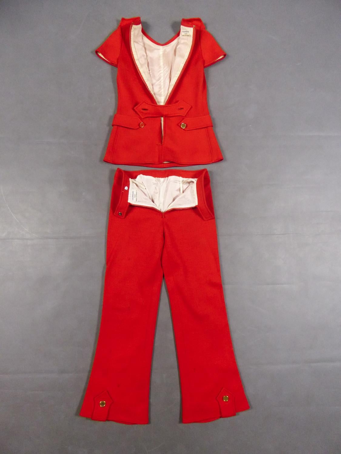 Circa 1972
France

André Courrèges Haute Couture tunic and pants set numbered 7852 and 7857 from the early 1970s. Thick coral red wool jersey entirely overstitched and lined with off-white nylon. Top with short sleeves, shoulder tabs and sewn waist