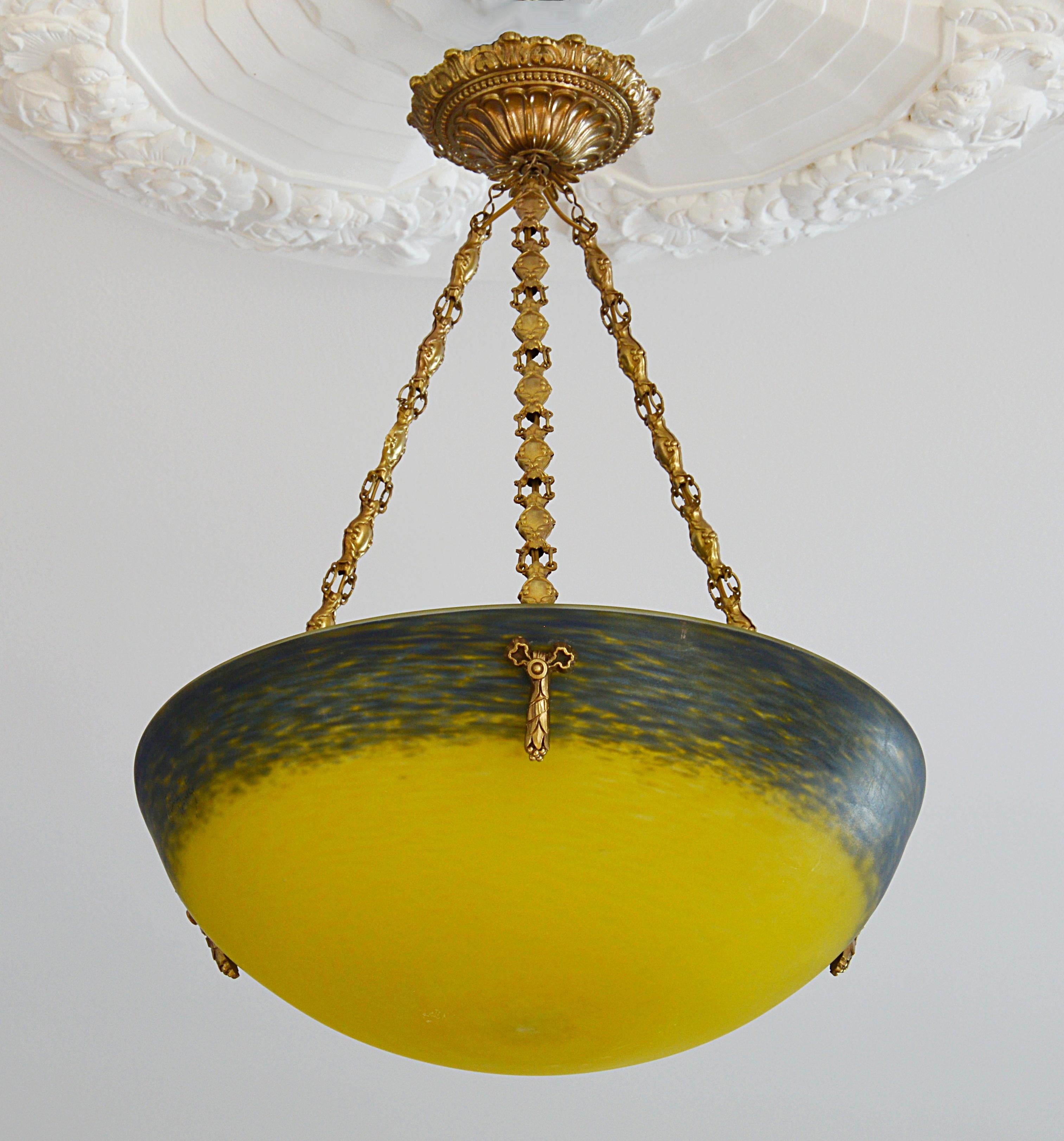 French Art Deco pendant chandelier by Andre Delatte (Jarville, near Nancy), France, late 1920s. Glass, solid bronze and brass. Mottled blown double glass lampshade. Colors: yellow and blue. Superb solid bronze (canopy and hidden-holes) and stamped