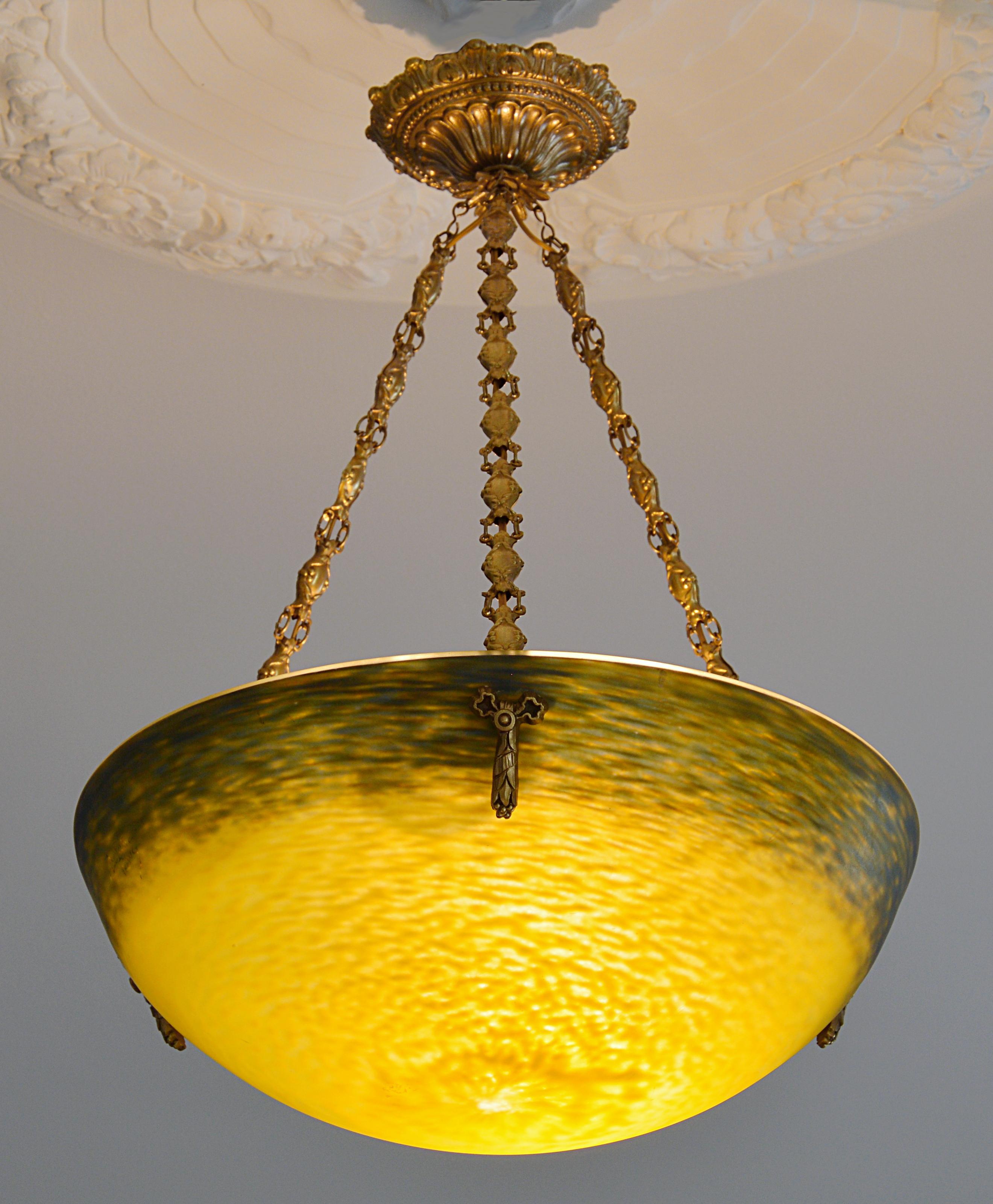 French Art Deco pendant chandelier by Andre Delatte (Jarville, near Nancy), France, 1920s. Glass, solid bronze and brass. Mottled blown double glass lampshade. Colors: yellow and blue. Superb solid bronze (canopy and hidden-holes) and stamped brass