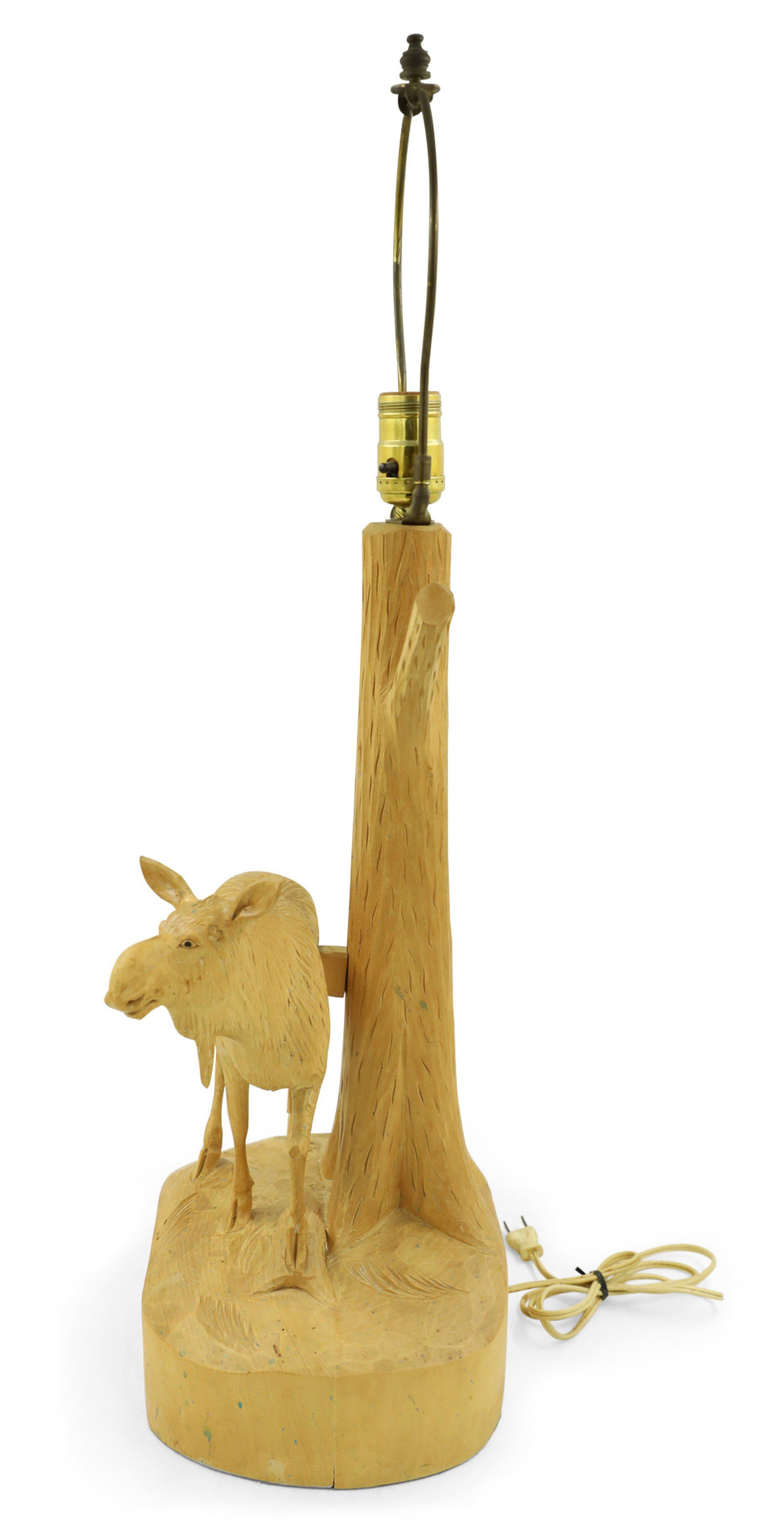 Rustic Adirondack style mid-century Canadian carved figural moose lamp with a carved tree trunk resting on a shaped base with a wooden slat shade. (signed: ANDRE DUBE).
     