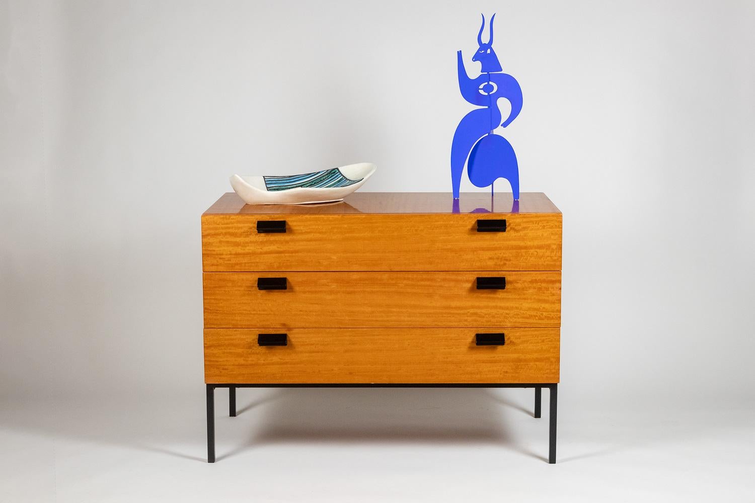 André Monpoix, by.

Chest of drawers in varnished blond cherry, opening with three drawers on the front, the first compartmentalized, with its base and handles in black lacquered metal.

French work realized circa 1960.

Dimensions: H 72 x W 100 x D