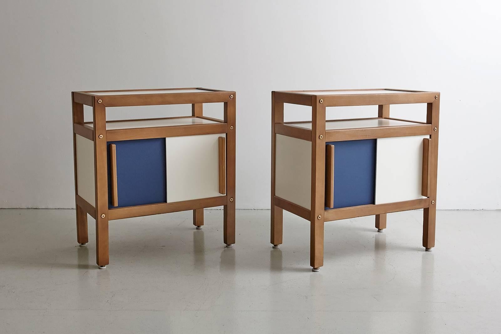 Pair of Andre Sornay end tables produced in 1950s, France. 

Constructed of teak wood, contrasting cobalt blue and white sliding doors open to reveal storage and extra shelf. Great wood handle detail.