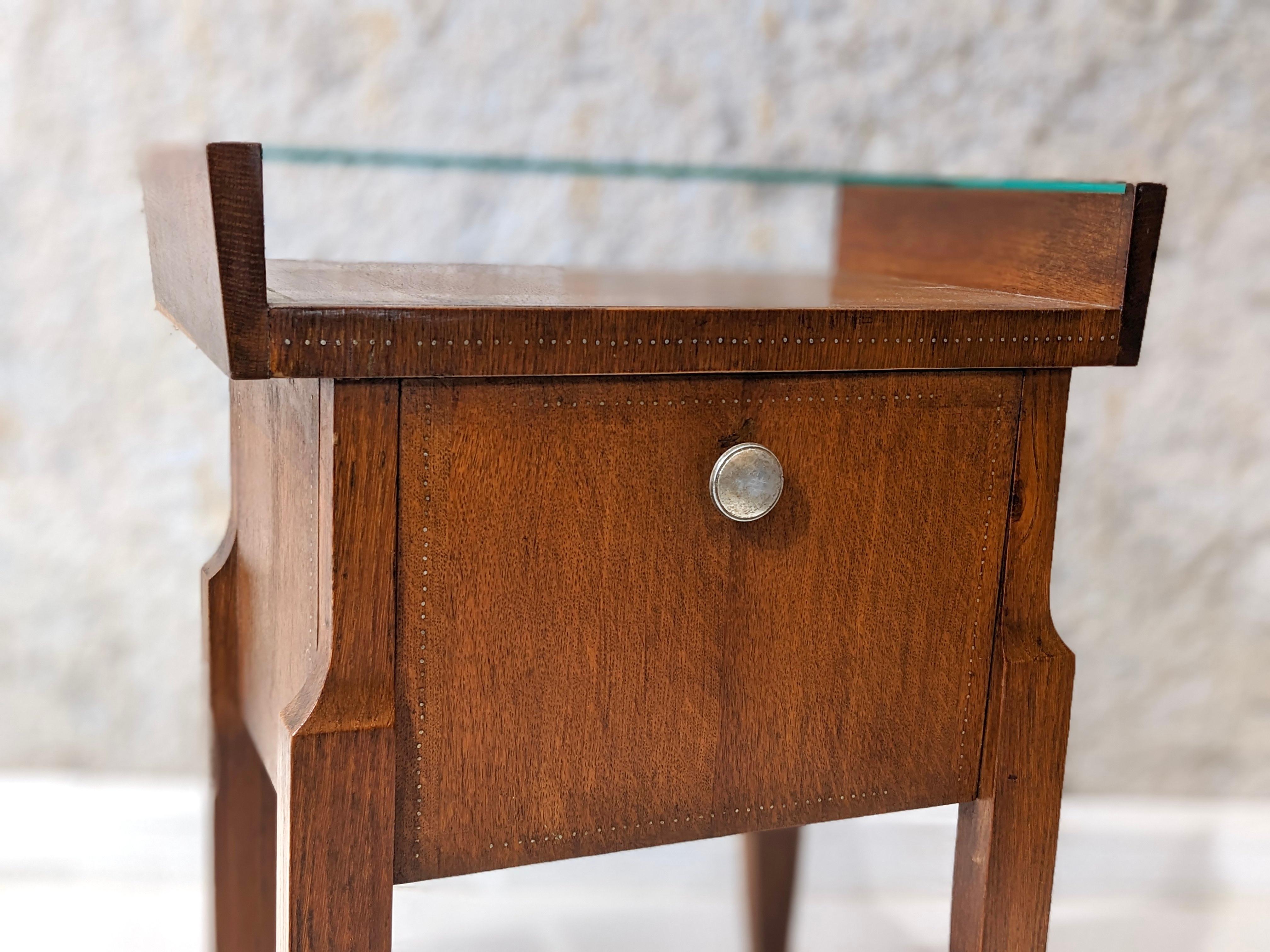 André Sornay walnut bedside table. 

Very good condition, circa 1940
The bedside table is in walnut. The nails are in brass, aligned, following all the contours of the furniture. Glass top.
Dimensions : W49.5 cm x D31 cm x H65 cm.