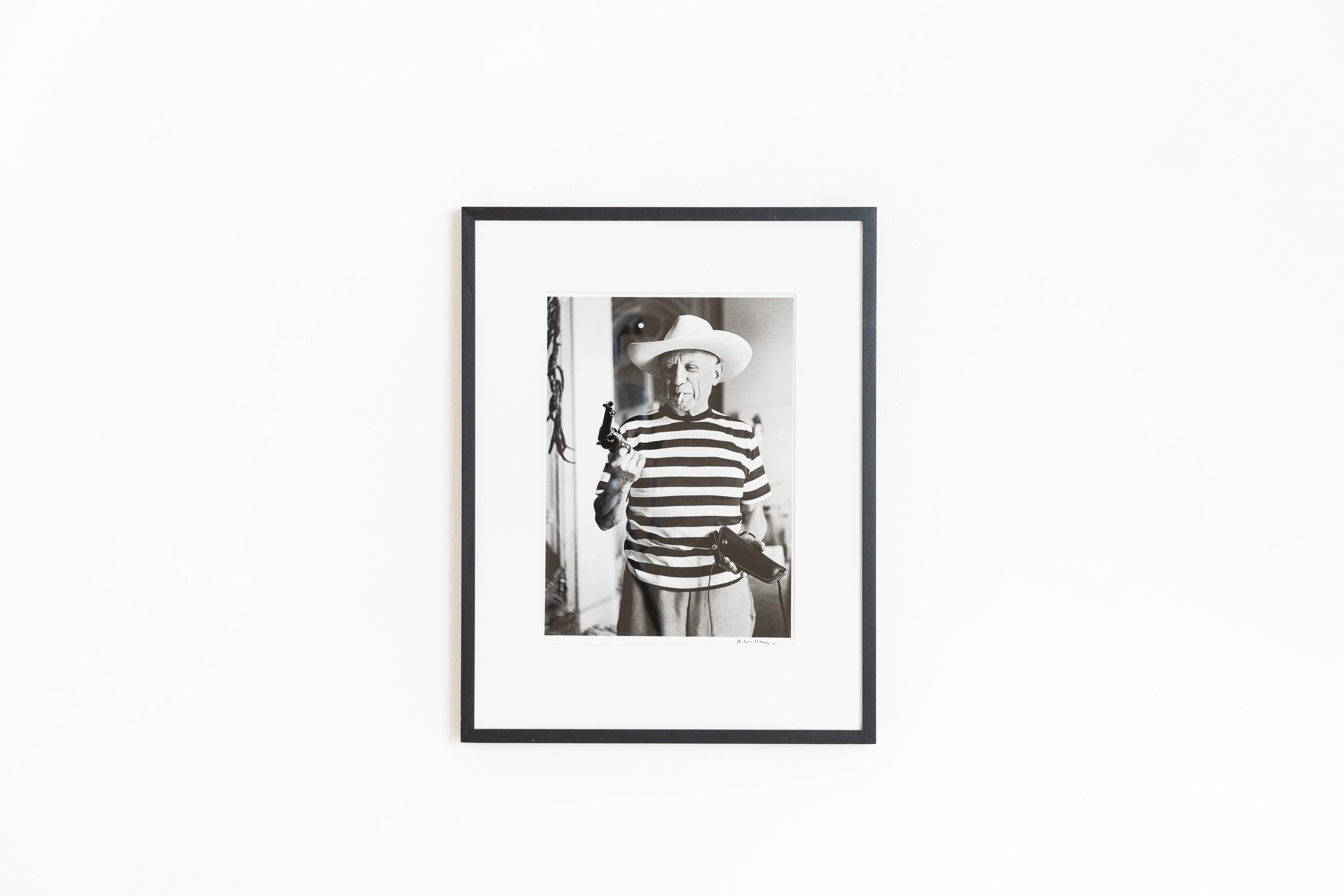 Famos Picasso - Portrait by André Villers, with the gun and hat, signed, original silver print. 
The gun, with which André Villers photographed Picasso here, was a gift from Gary Cooper to Picasso. Gary Cooper and his family (wife and daughter Mary