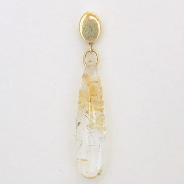 These unique earrings feature luxurious drops of golden rutilated quartz on a 10 karat gold stud and post earring.  The stones are 6mm wide and x 26mm long and feature delicate golden coloured rutile needles. 