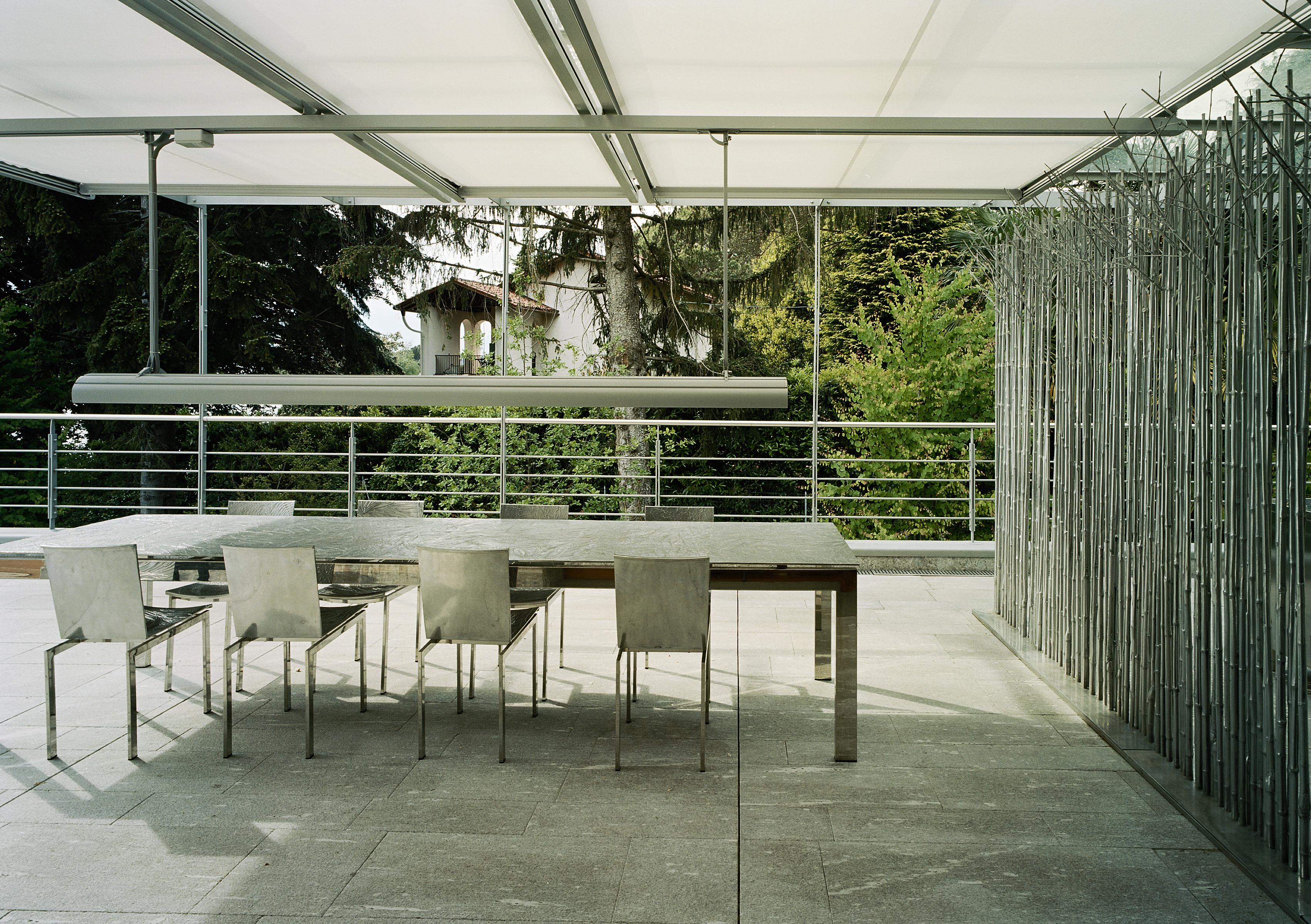 Table de salle à manger en fonte d'aluminium pour Dilmos Milano. La structure est réalisée en acier inoxydable brillant et le plateau est en fonte d'aluminium. La surface est créée avec des panneaux en fonte d'aluminium avec une texture d'aiguilles