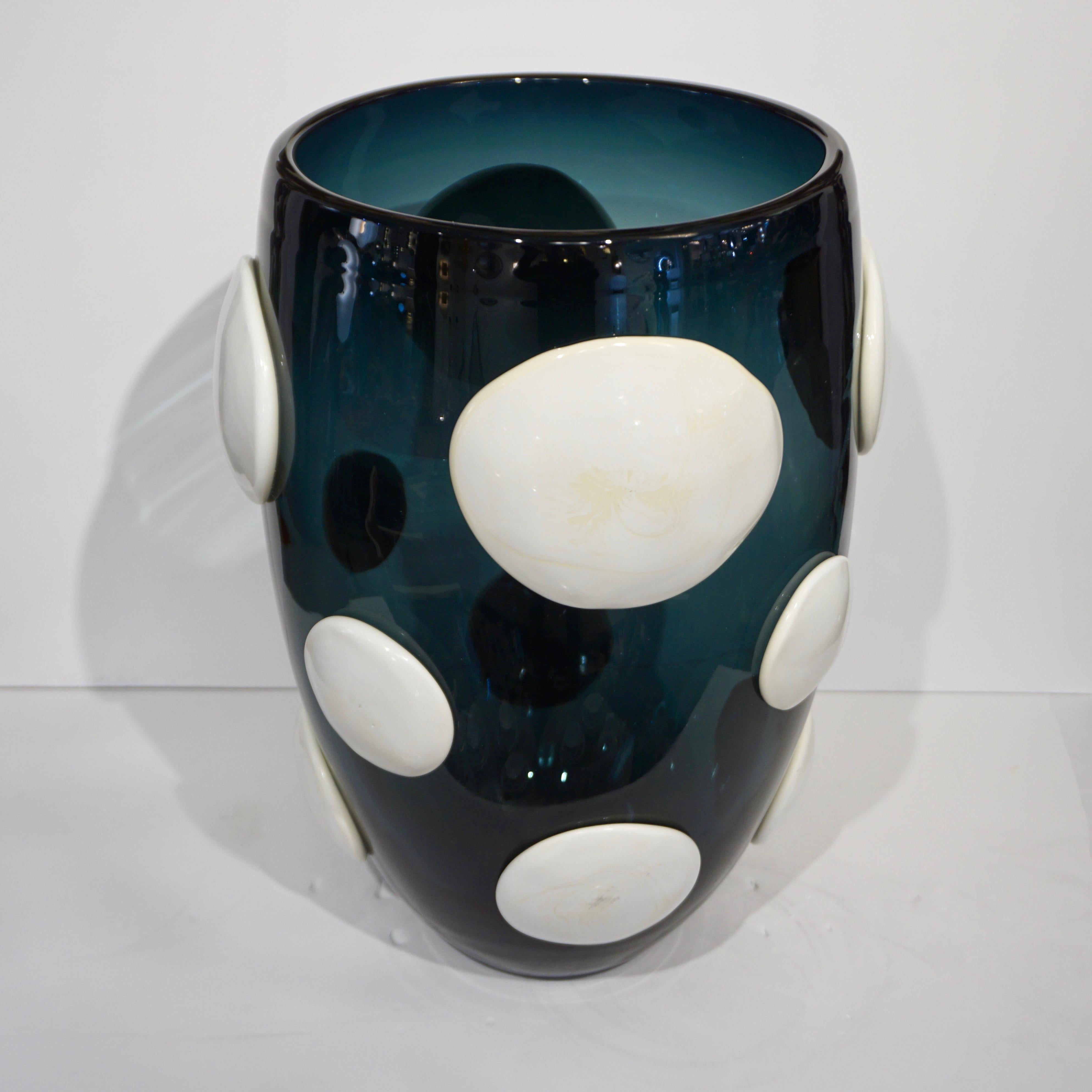 A monumental blown vase by Andrea Zilio, in a rare smoked navy teal Murano glass with a transparency that picks up aquamarine tinted reflections, decorated with polka dots in white glass paste, circa 2000, Italy. Signed piece.
Diameter of the rim: